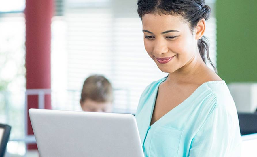 a woman looking at a computer screen and smiling