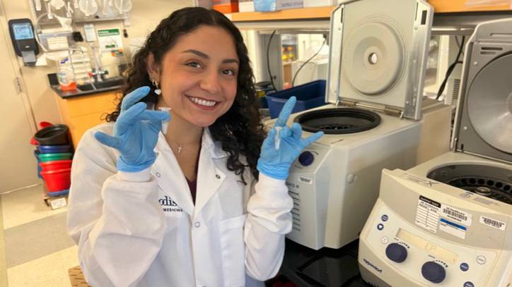 Patricia Garza poses for a picture in the lab with a white coat.