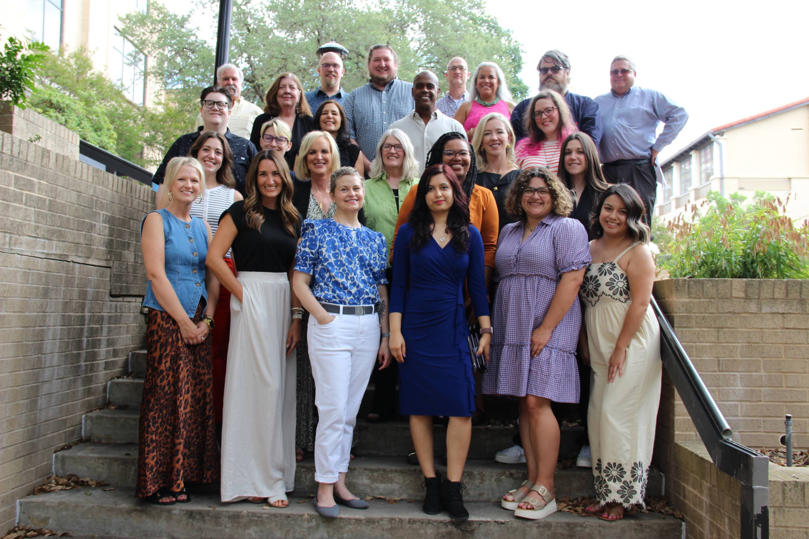 com studies faculty posing for group photo on the stairs outside Centennial Hall. 