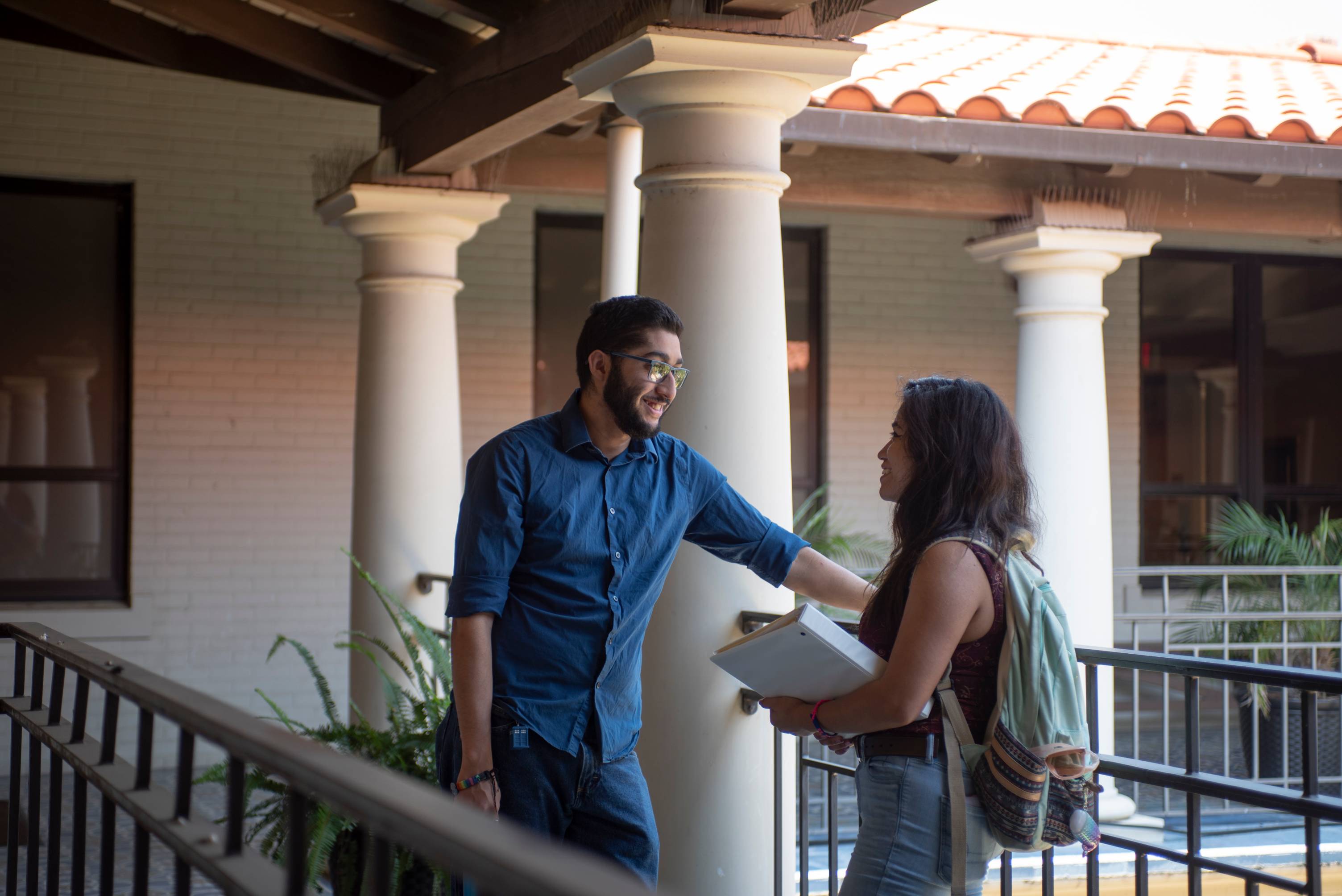 Two students talking in a courtyard.