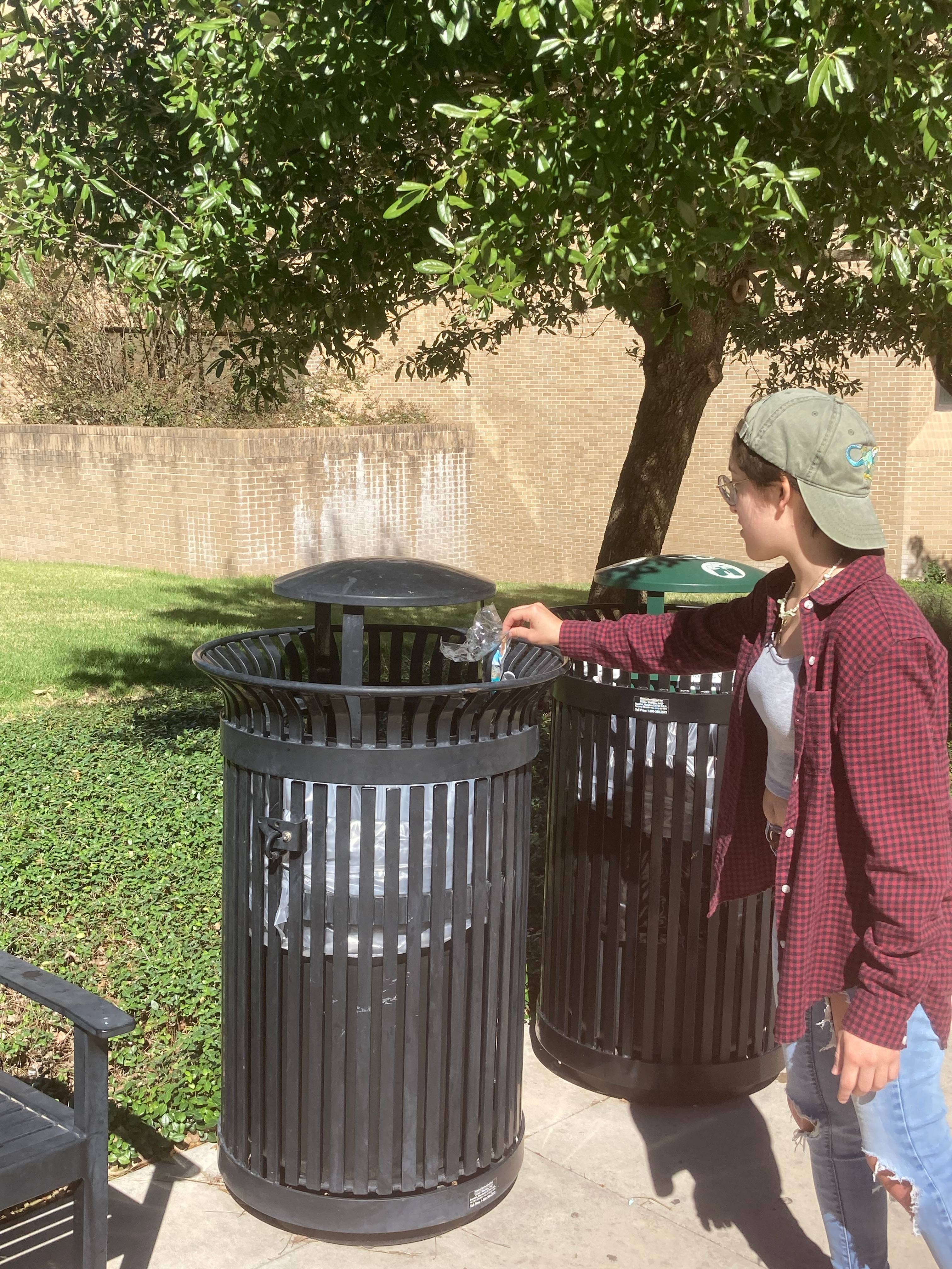 Student places trash in a trash can found along the Bobcat Trail
