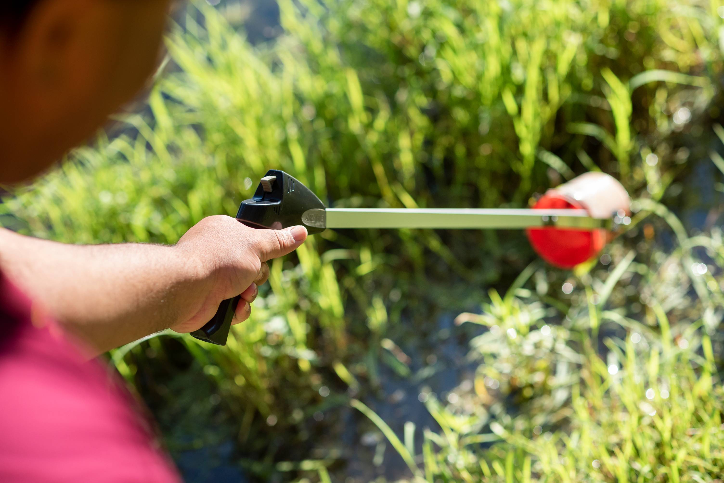 Student remove litter from one of the JCK ponds using a liter grabber