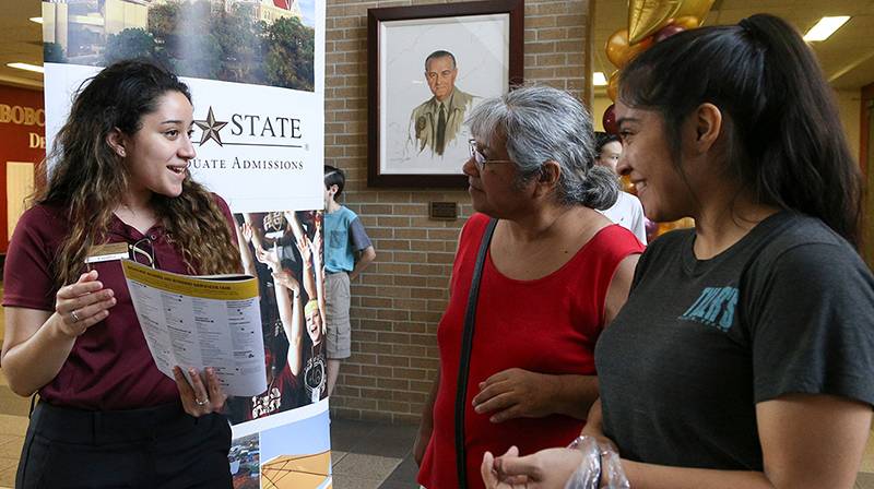 A student worker provides two women with a flier