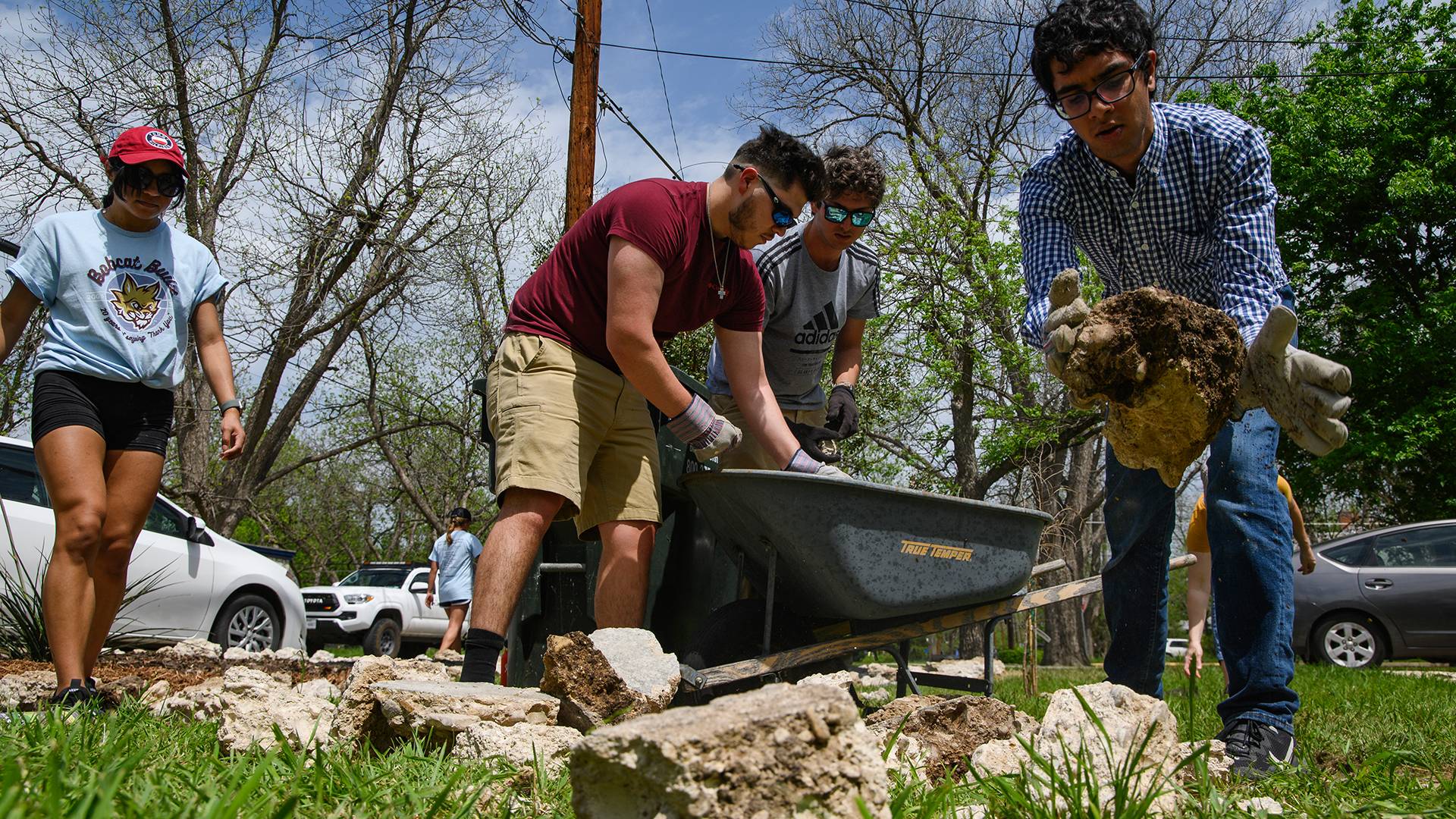 student volunteers picking up trash from a front yard