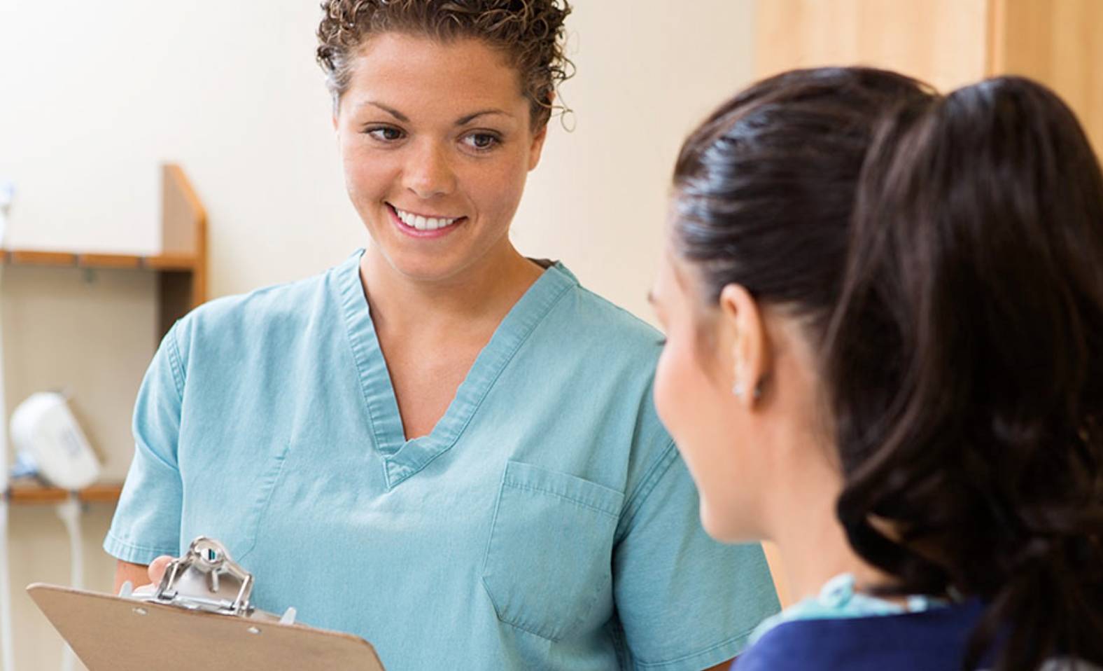 nurse with clipboard smiling at another nurse