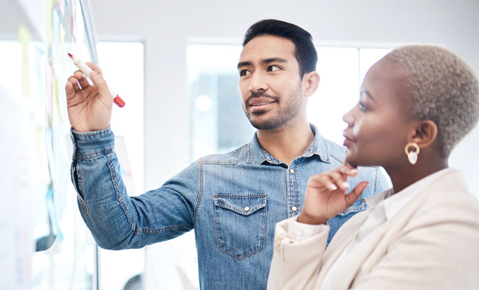 People standing over a desk with lots of paperwork on it.