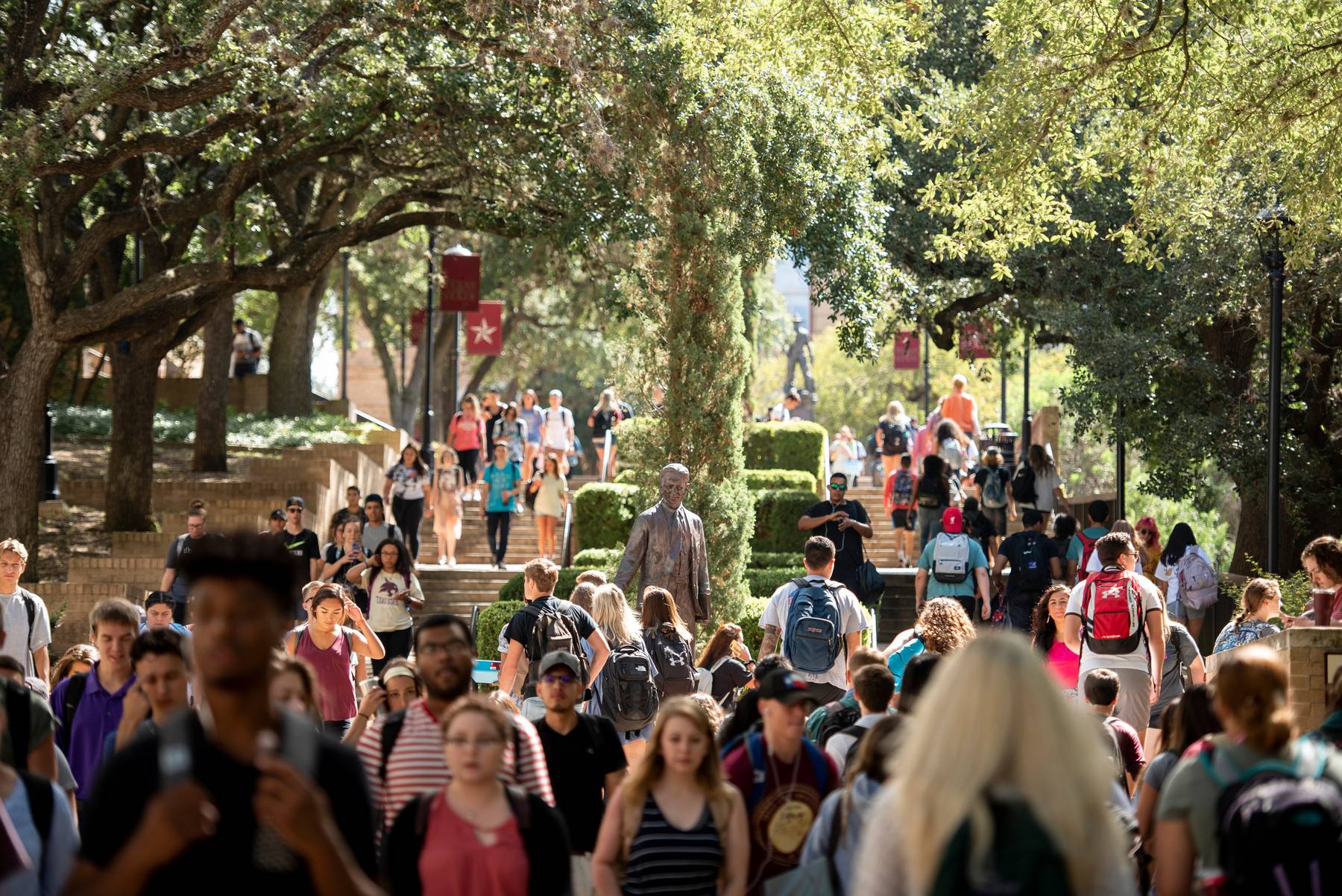A group of students walking through the Texas State University campus