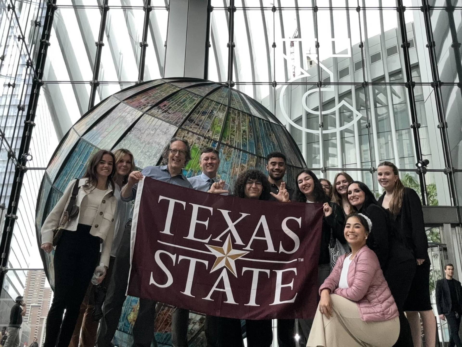 TXST students in NYC holding TXST flag