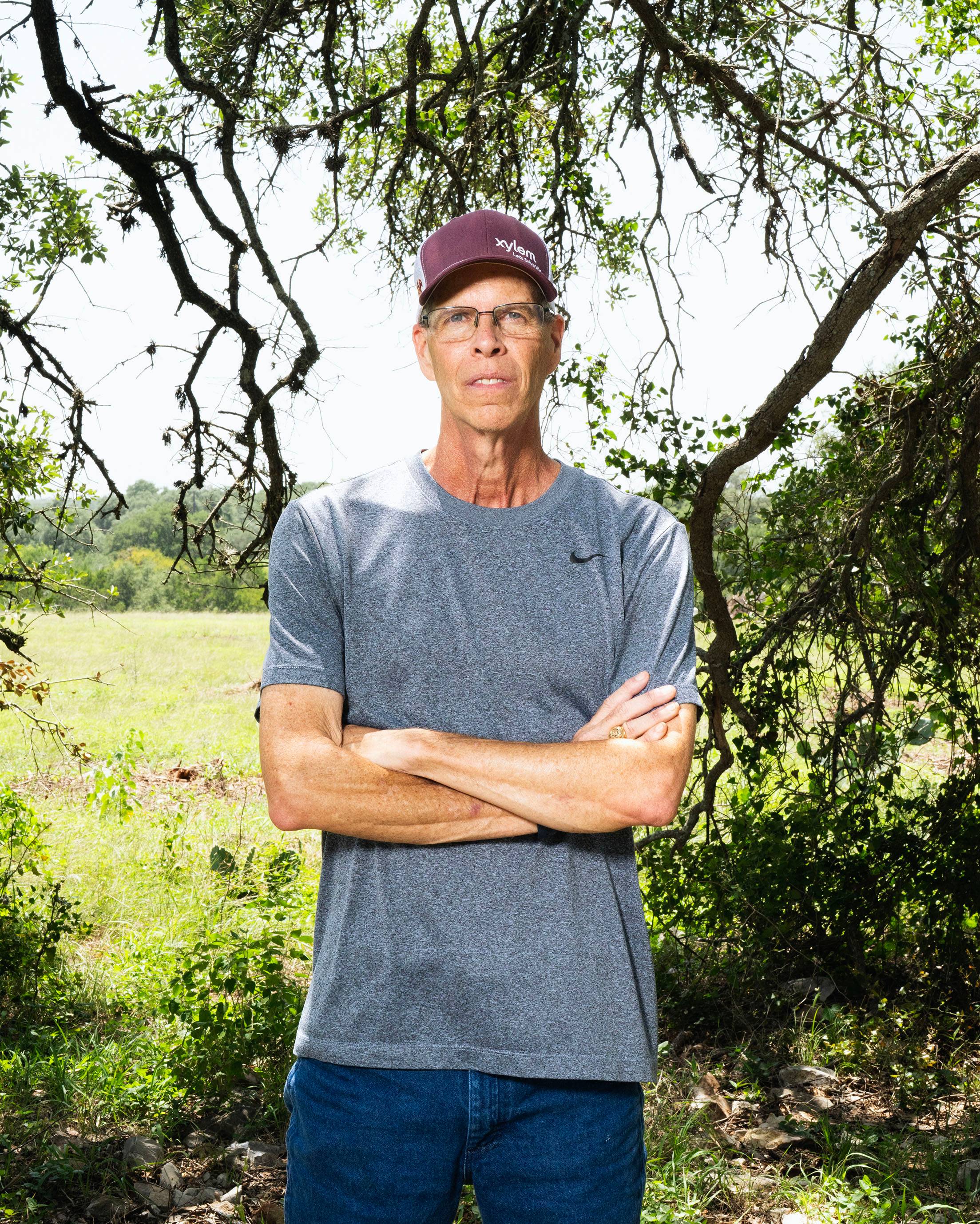 Brian Bruner standing under gnarled branches of of live oak tree.