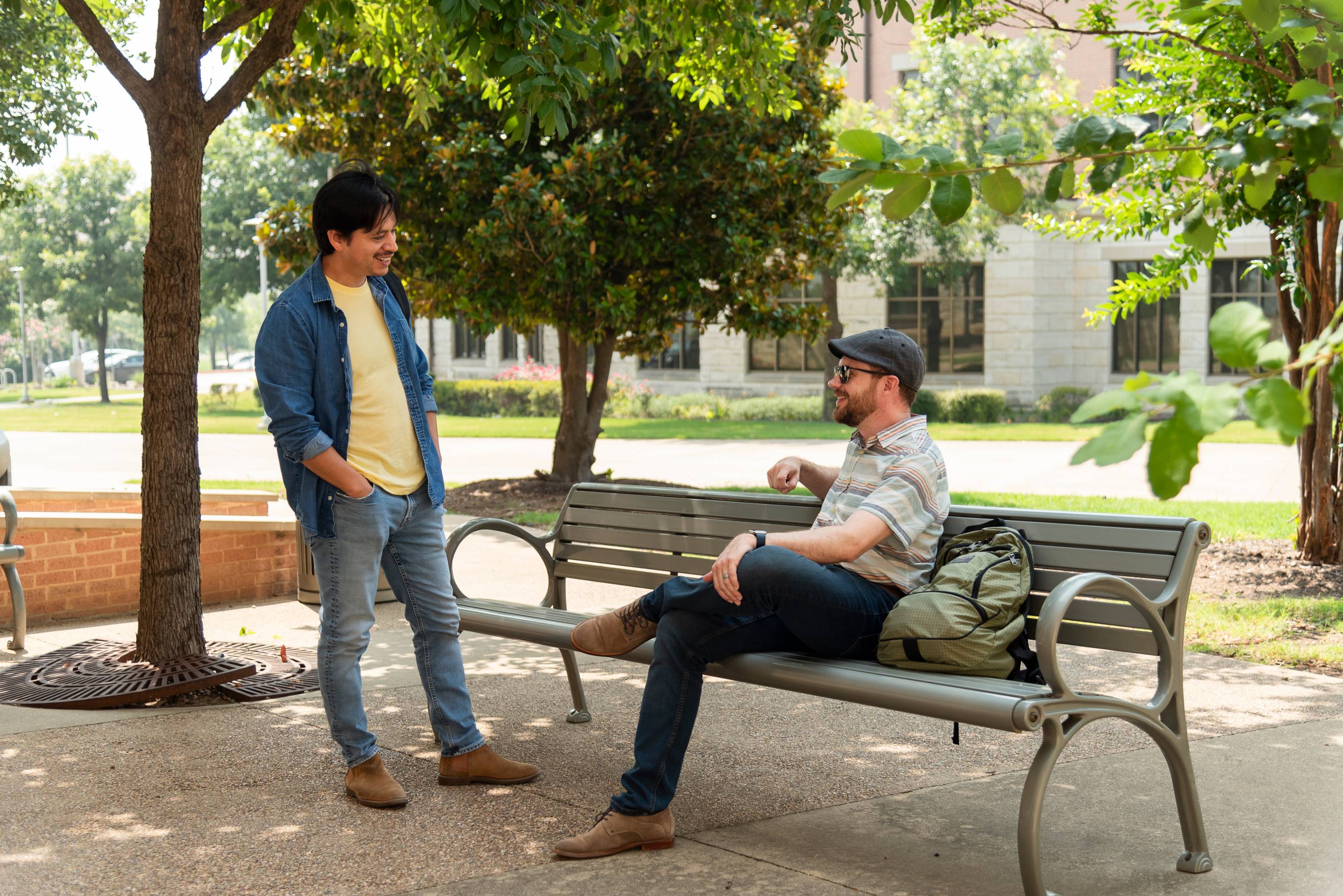 2 students at a bench talking, one sitting and one standing