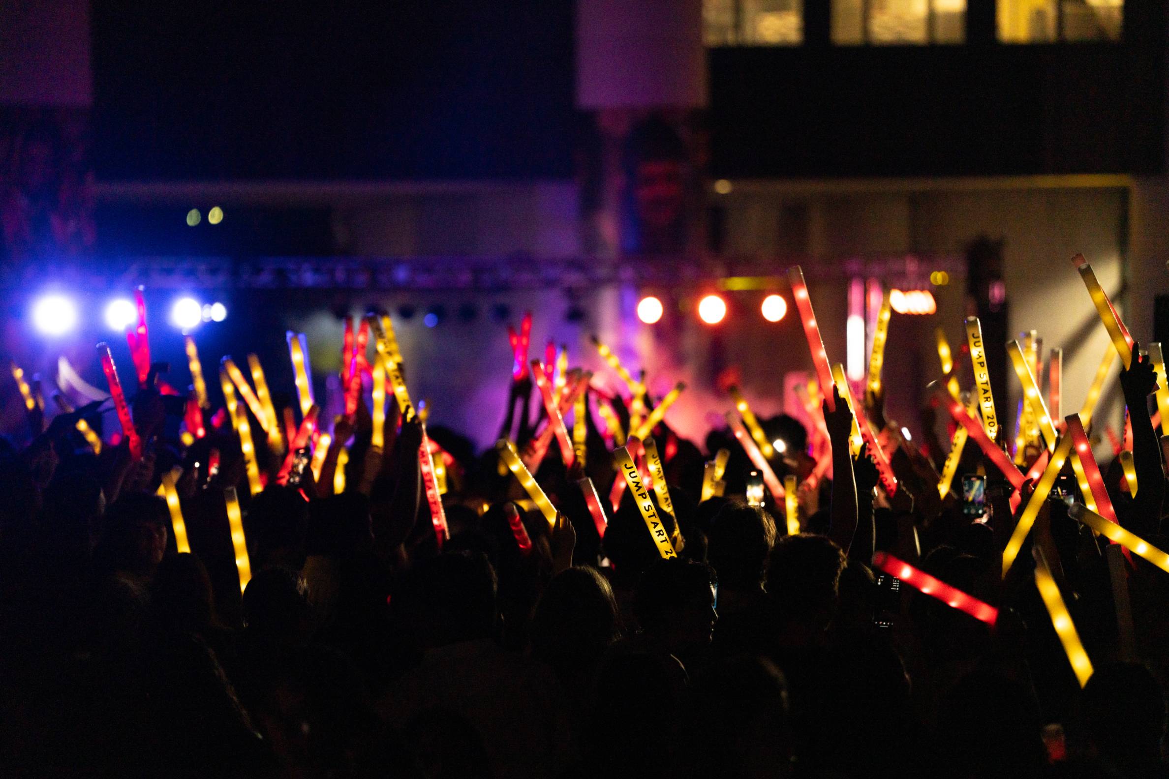 crowd of students at a stage holding up glow sticks that say jumpstart 2025