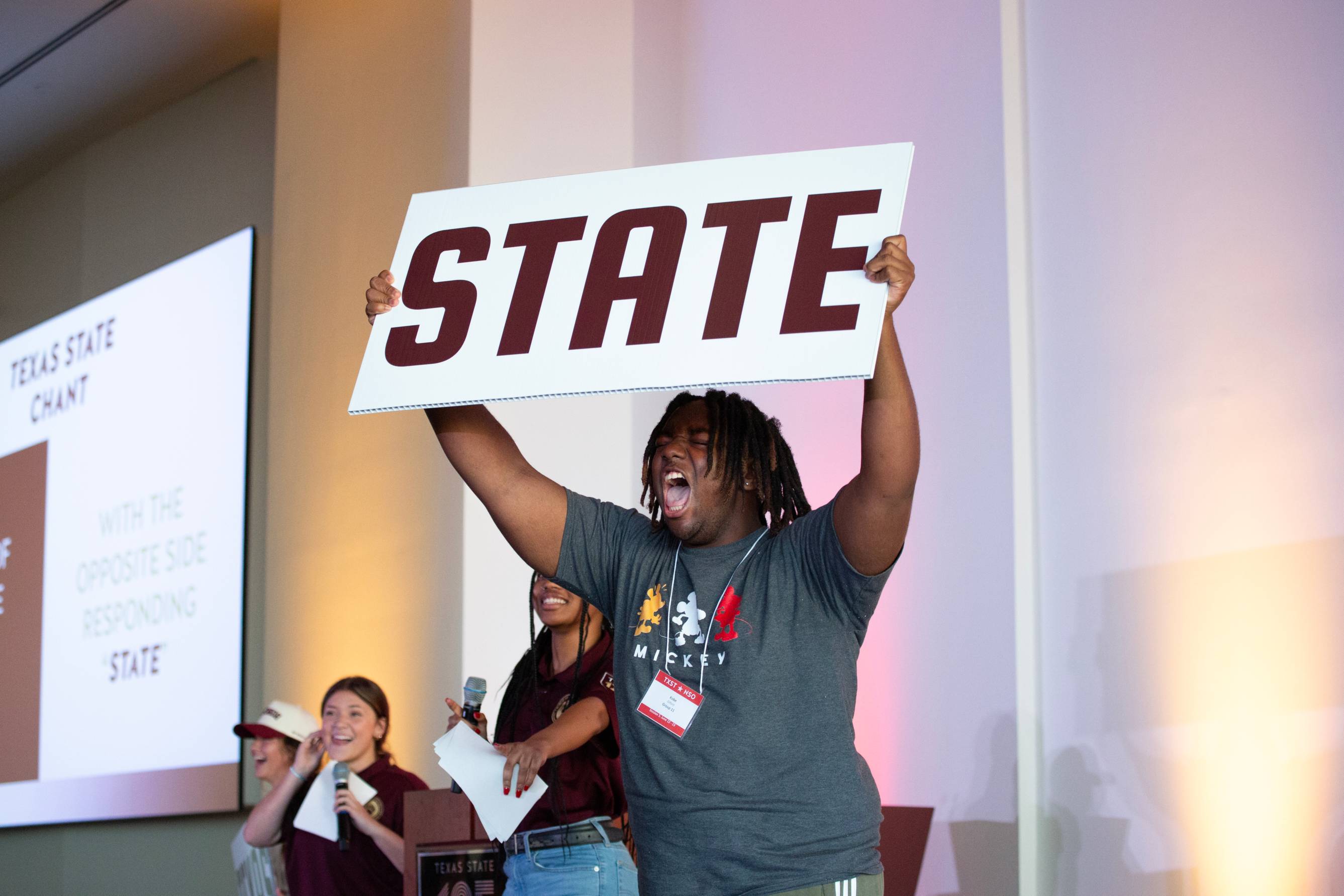 student holding up a sign that says "STATE" At NSO