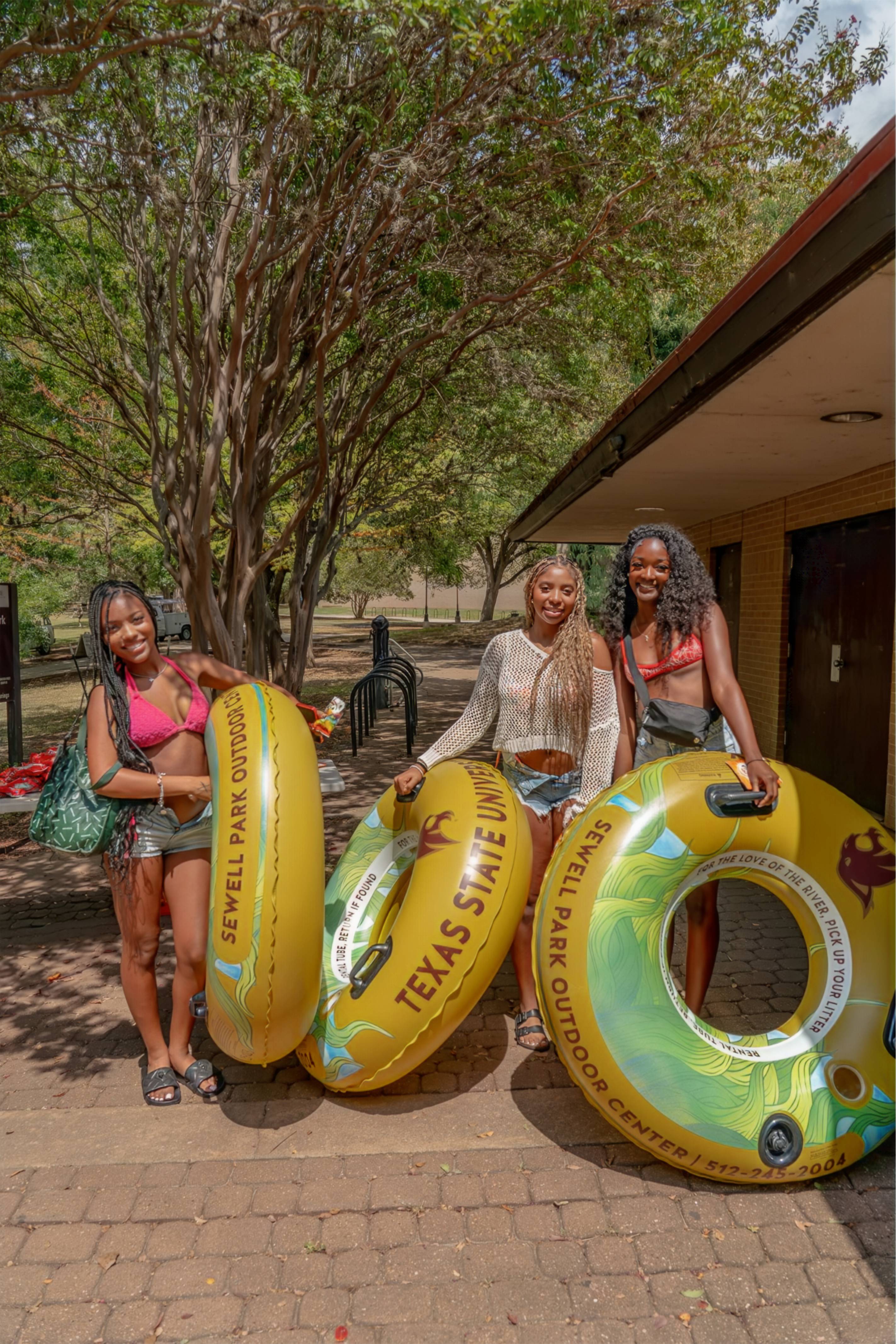 Three university students posing with inner tubes