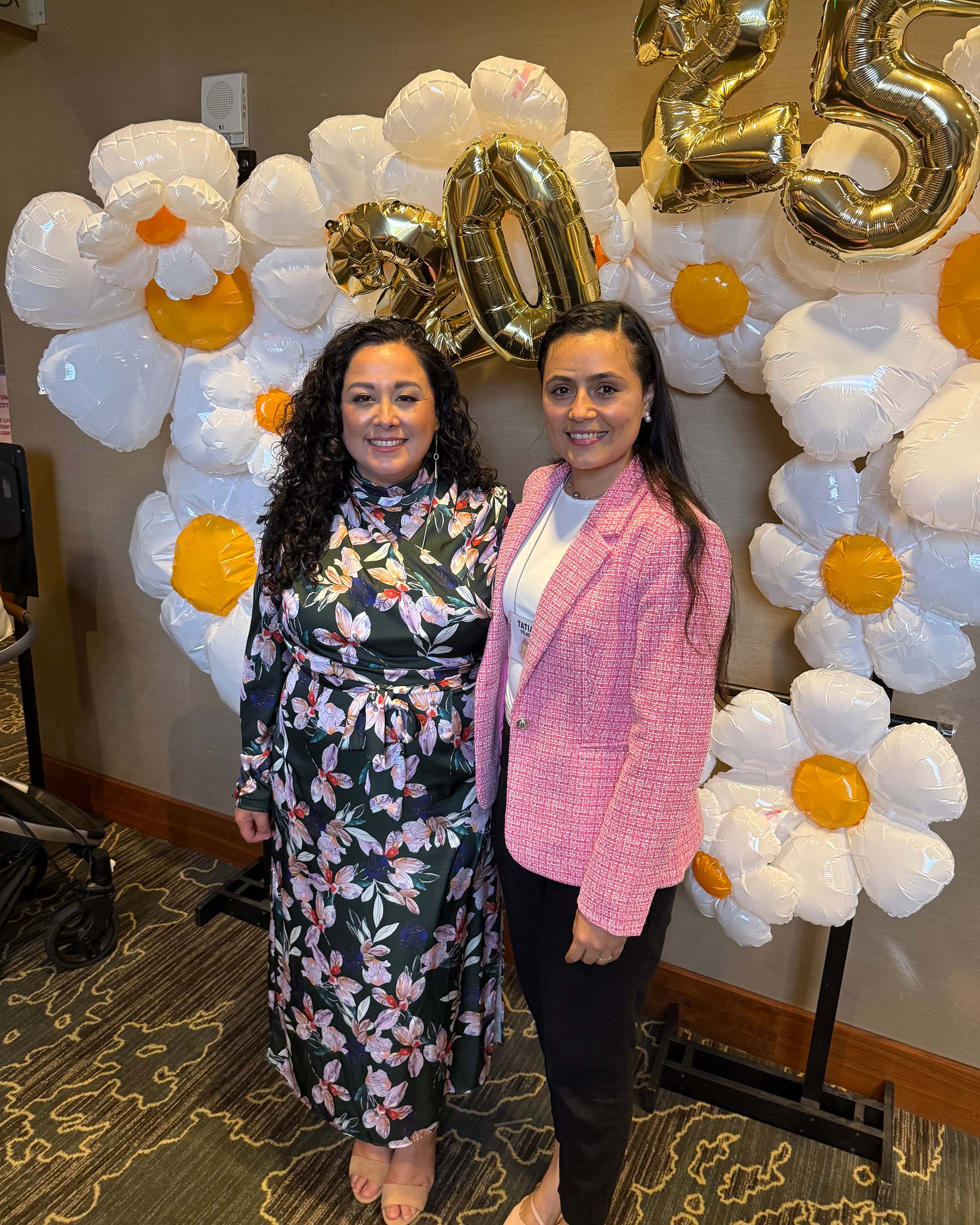 Andy Piñon (left) and Tatiana Velásquez-Roa pose for a picture in front of a balloon backdrop.