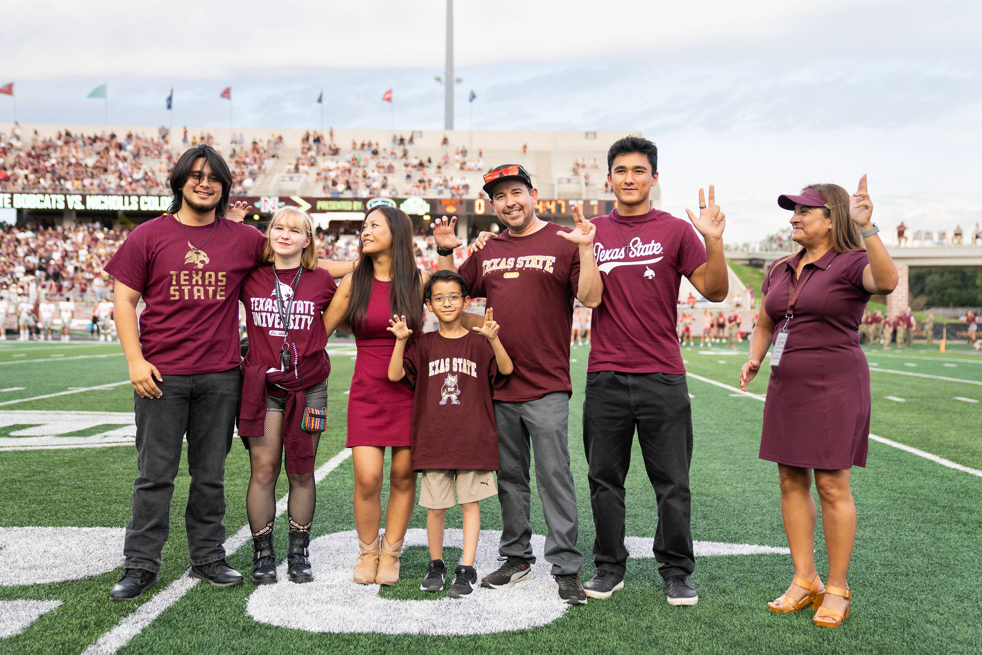 The Smith and Menchaca houshold pose for a photo on the football field.