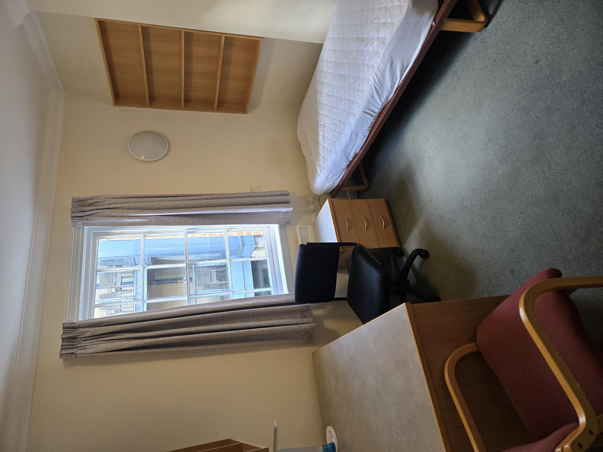 small bedroom with desk, chair, window, and bed.