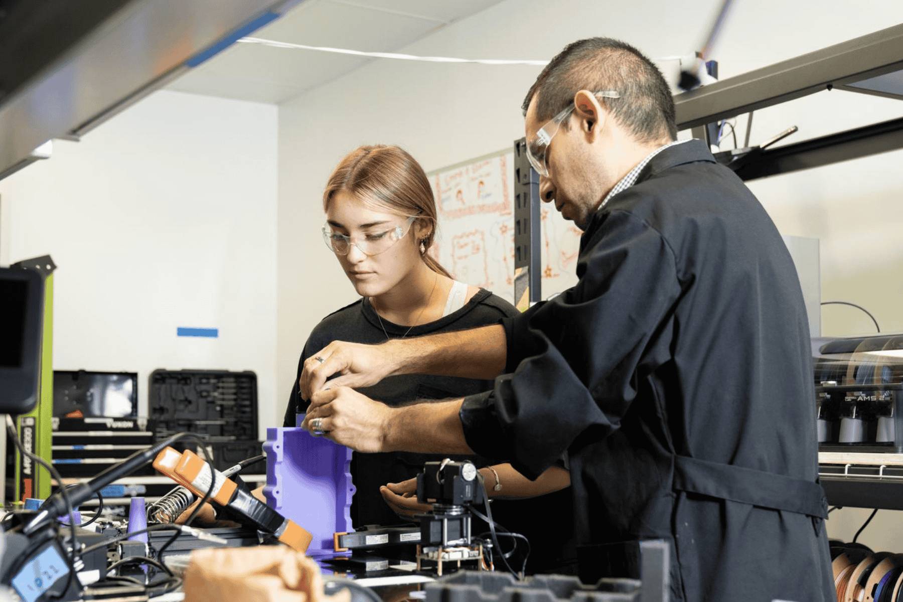 A student welding a piece of metal while sitting at a table