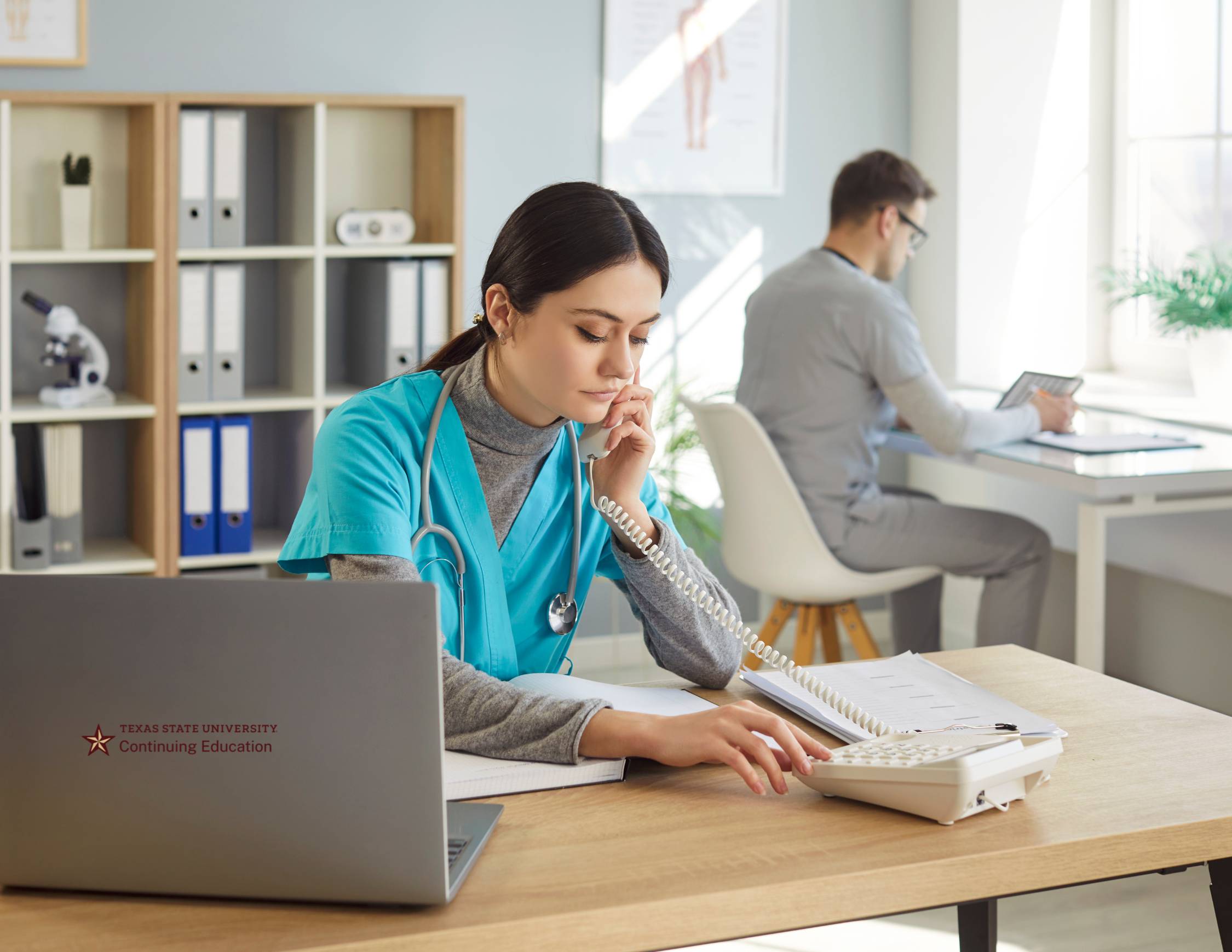 two medical assistants at desks working