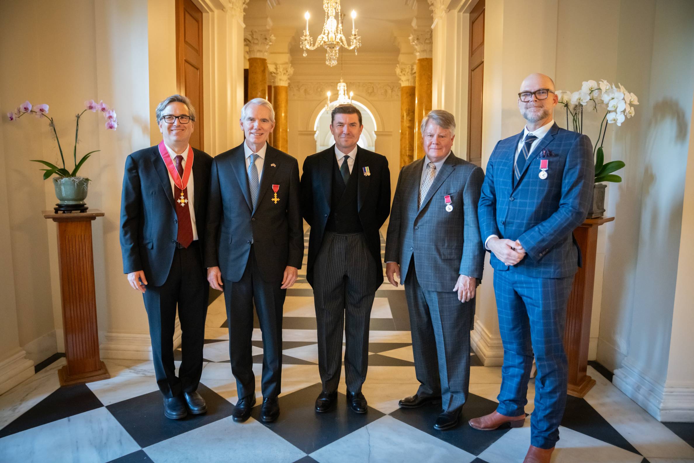 a group of men posing for a group photo in a british palace