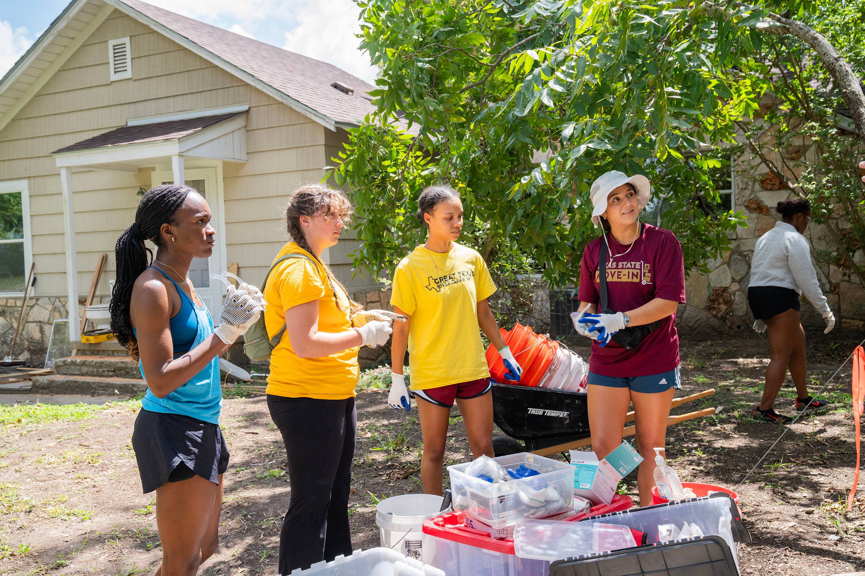 Four women stand together listening to someone off camera.