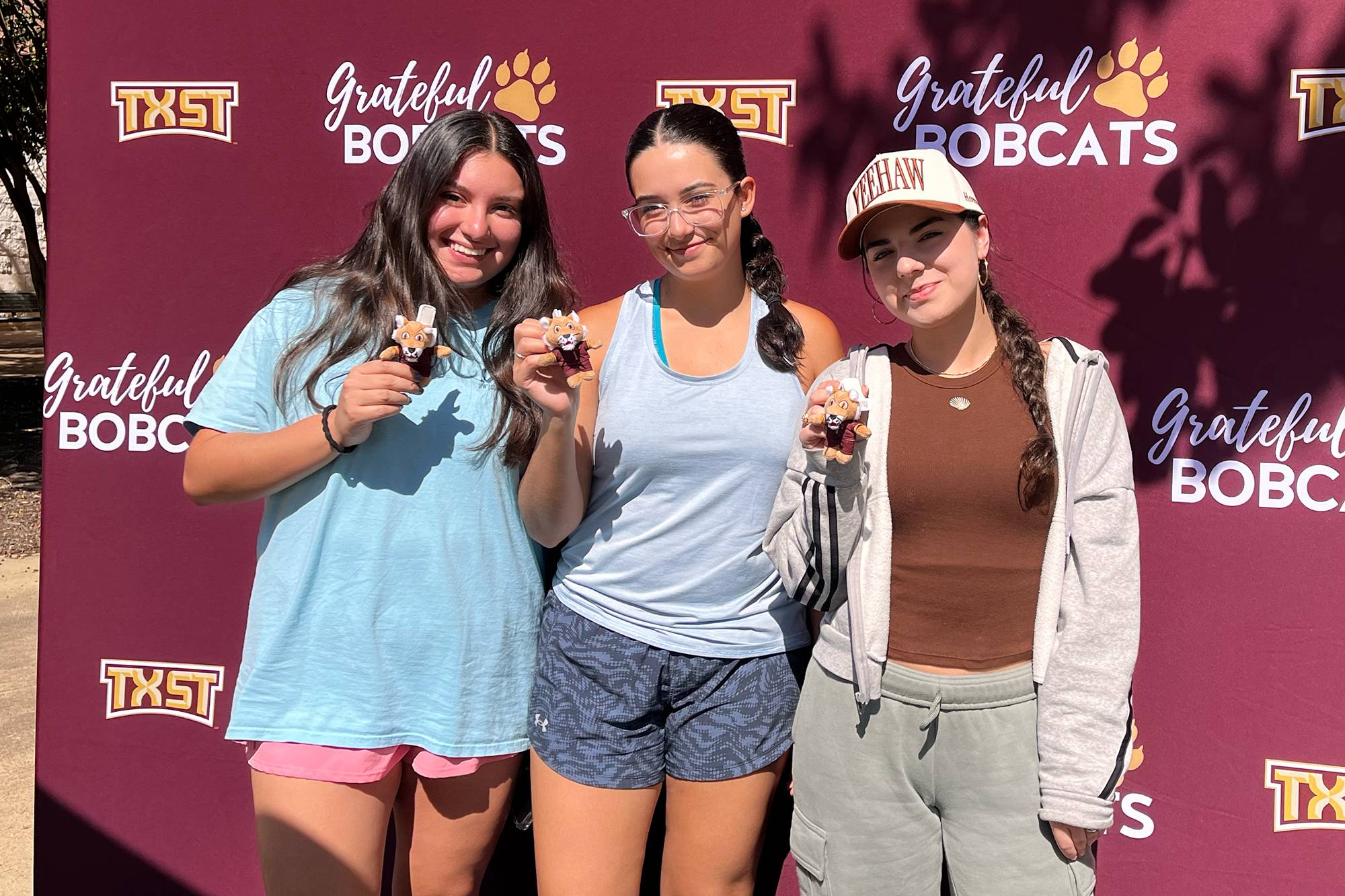 Students in front of a grateful bobcats banner with mini boko plush keychains