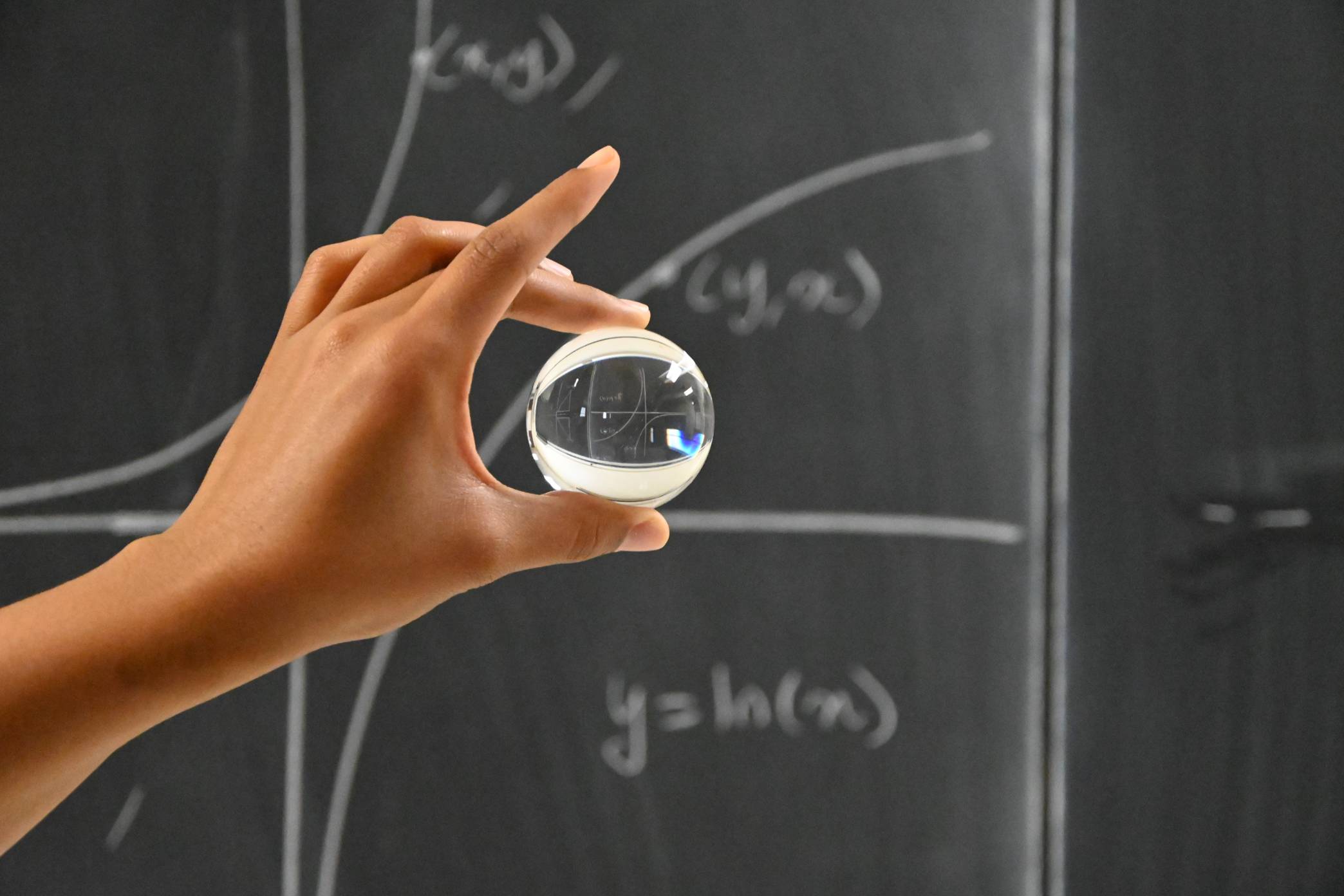 Glass ball held in front of math on chalkboard