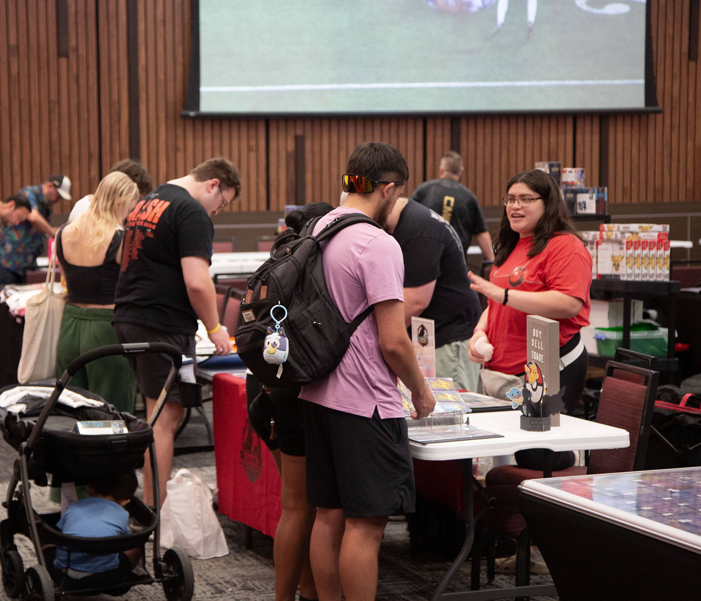 Several people standing over and looking at a table with trading cards.