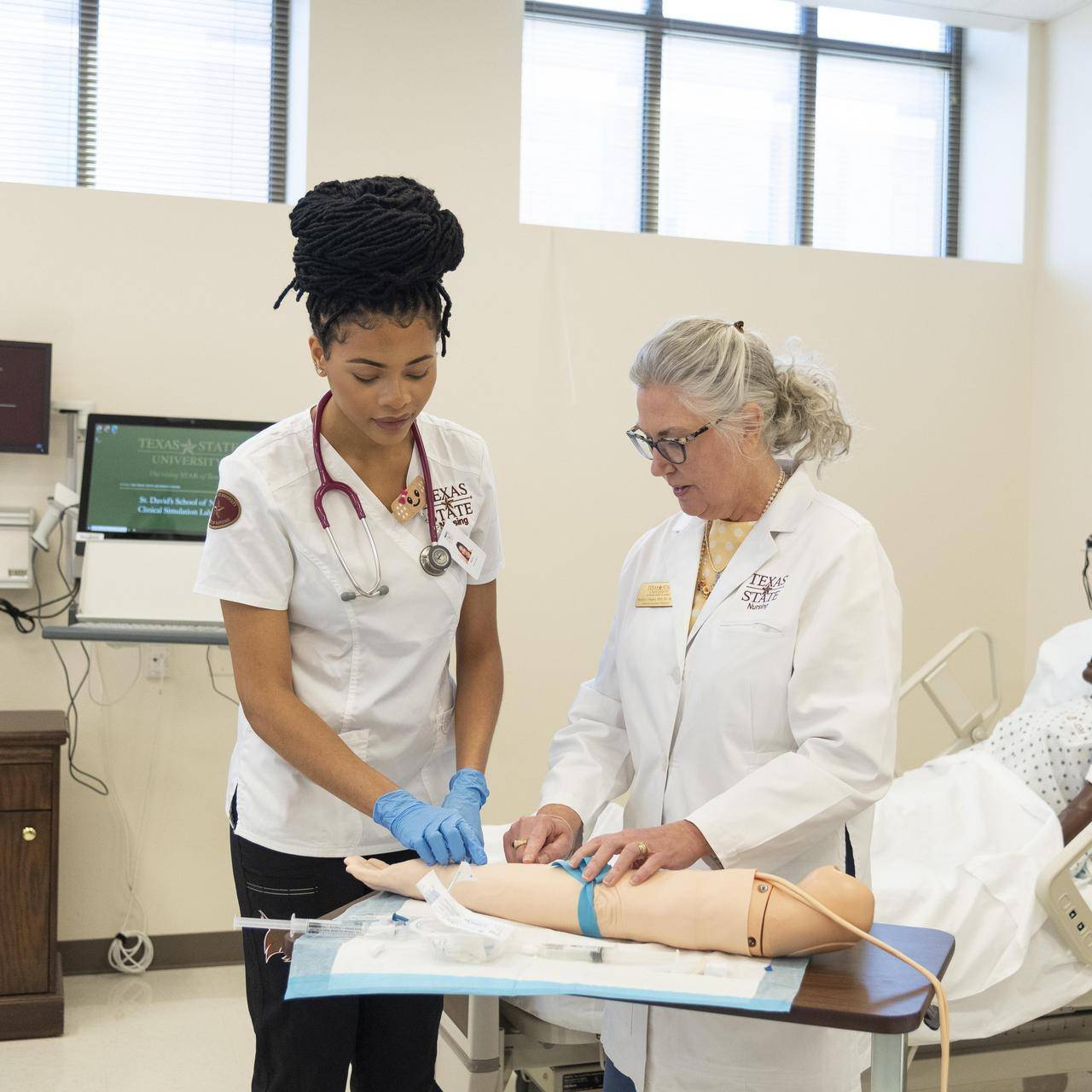 A nursing student and faculty member practice a procedure.