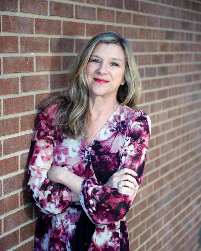 a woman standing next to a brick wall