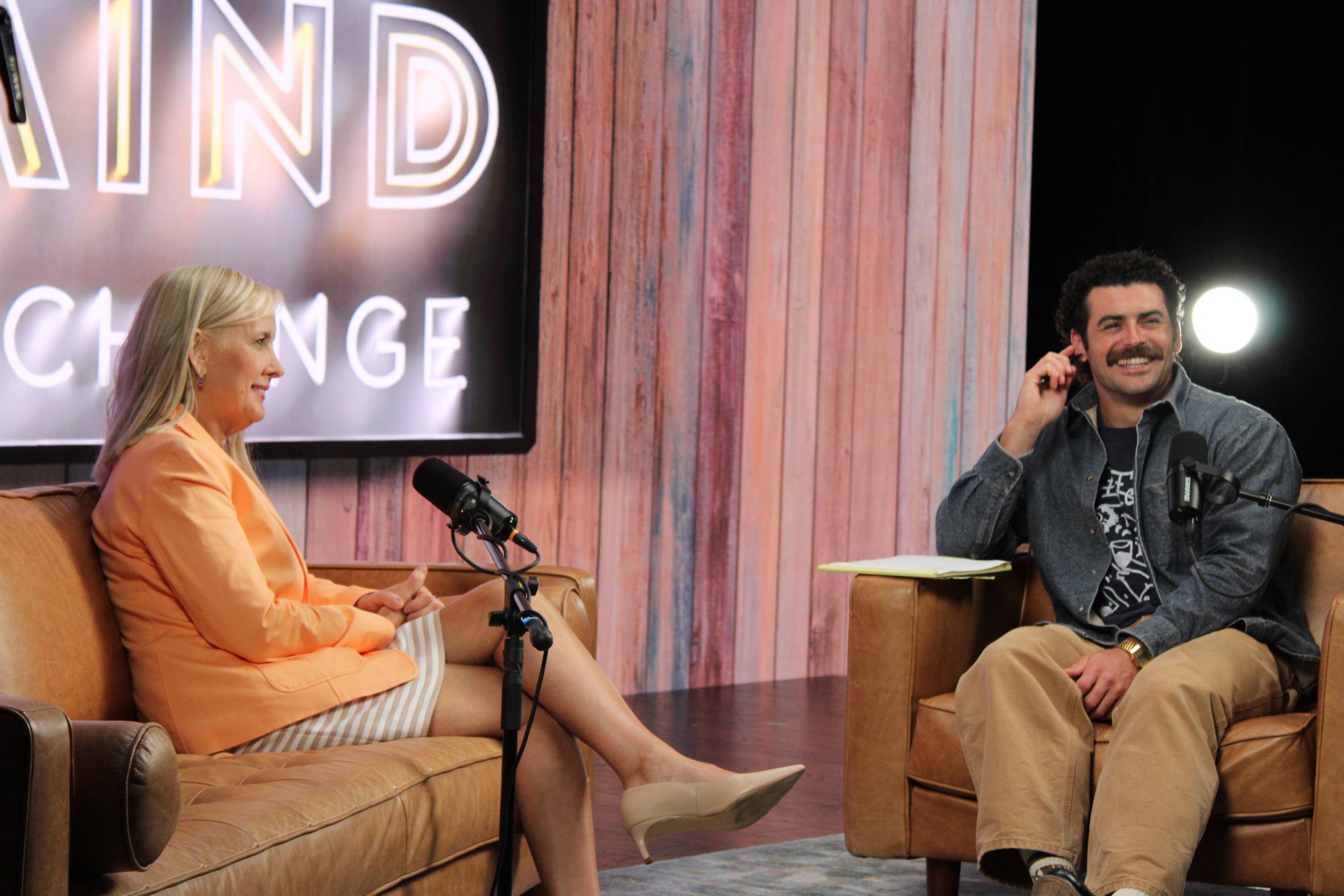 Dr. Melinda Villagran and Cody Gould sit on stage at the set of the Texas Mind Exchange podcast.