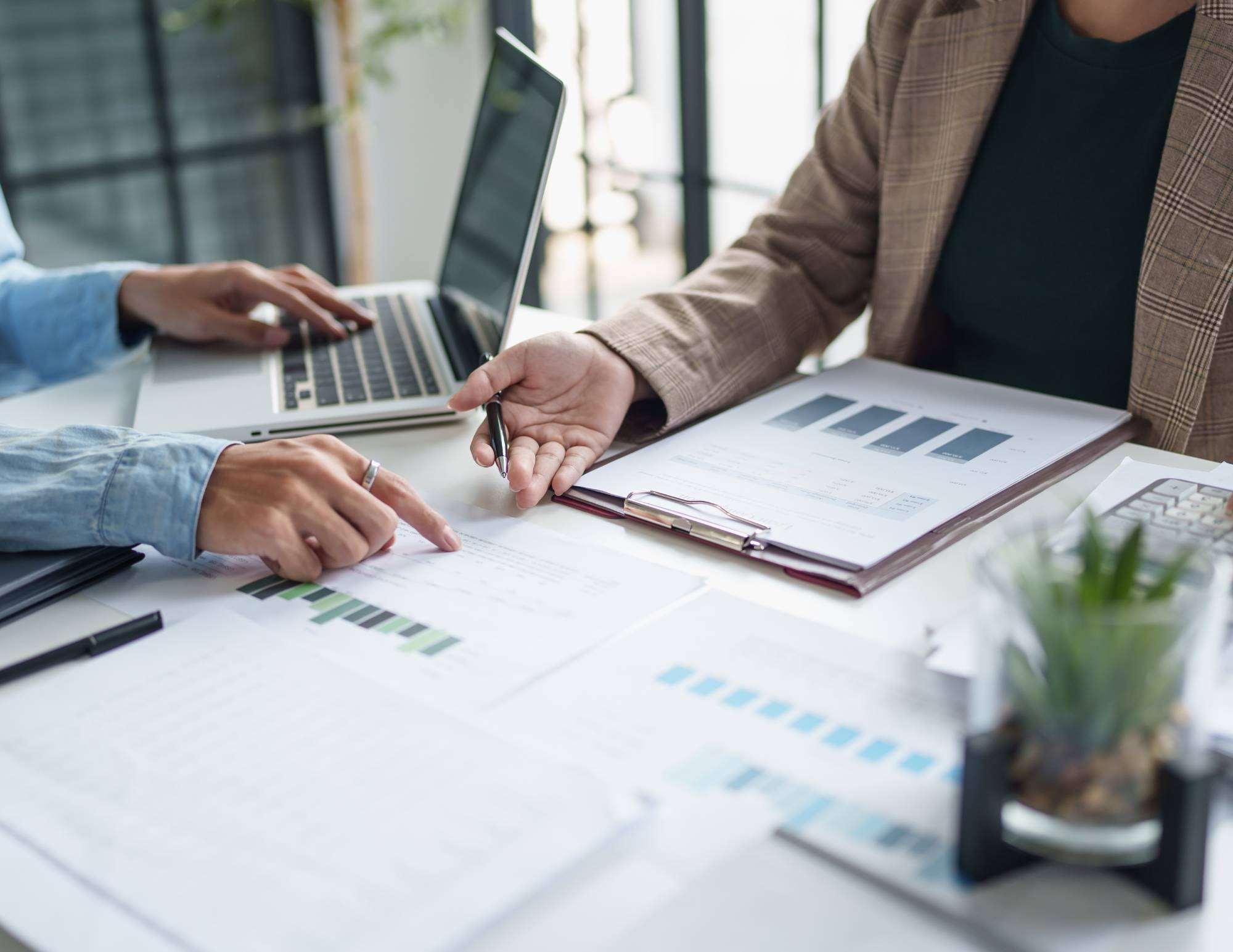 two people talking with paperwork and a laptop on the table