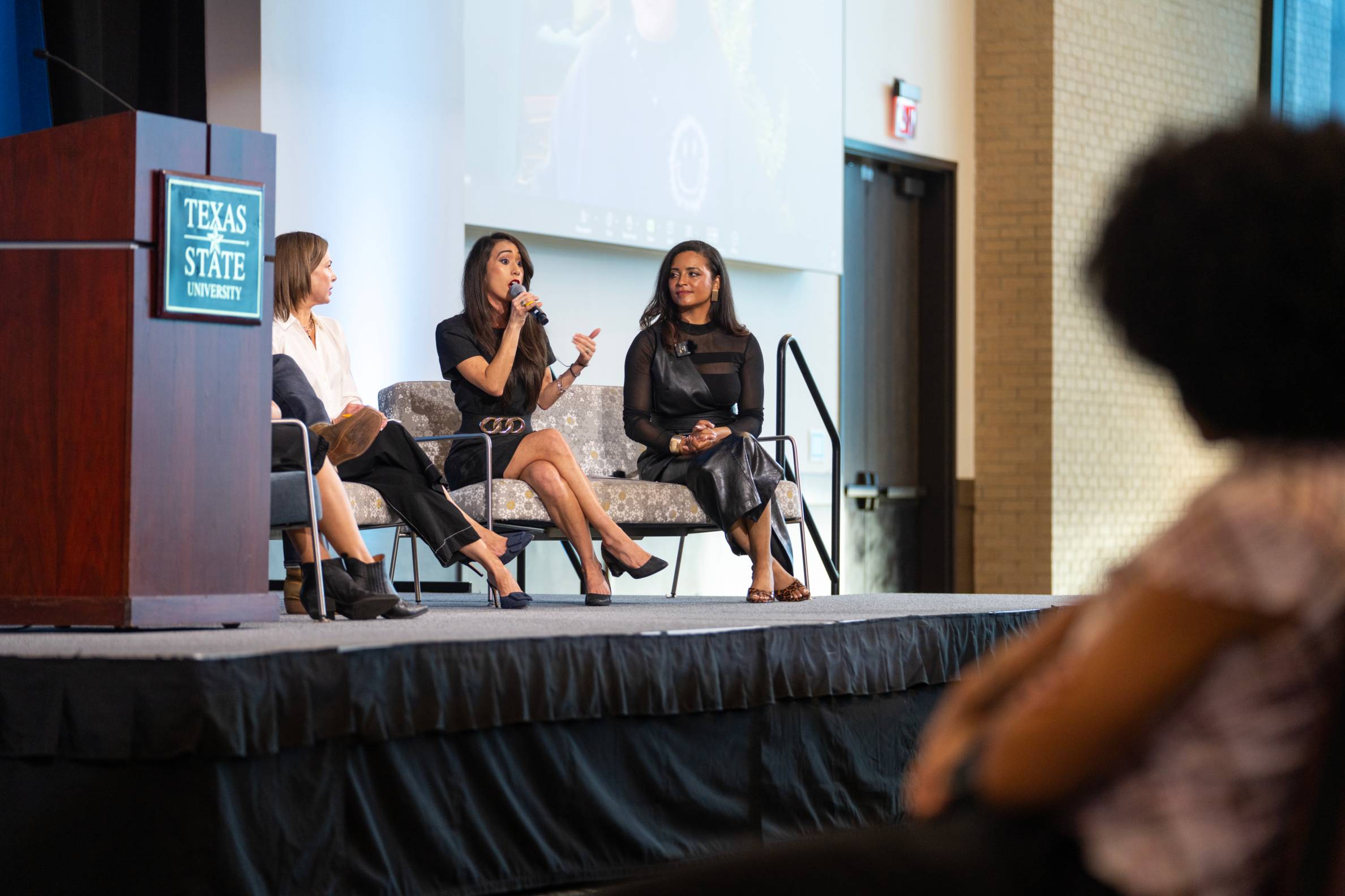 Panel of two speakers and a moderator on the stage in front of students.