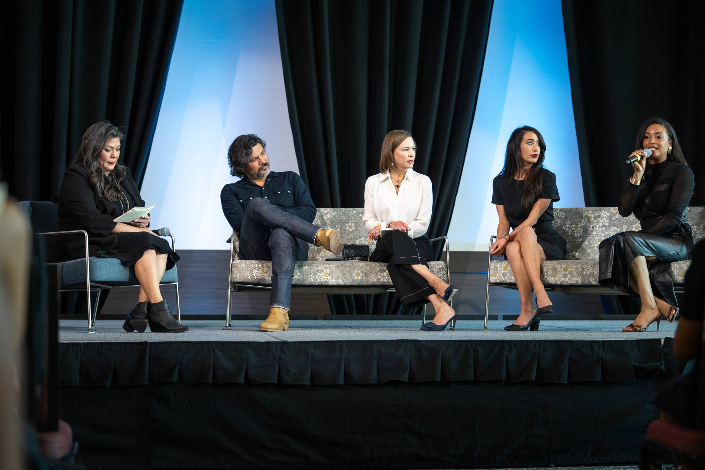 Panel of four speakers and a moderator on the stage in front of students.