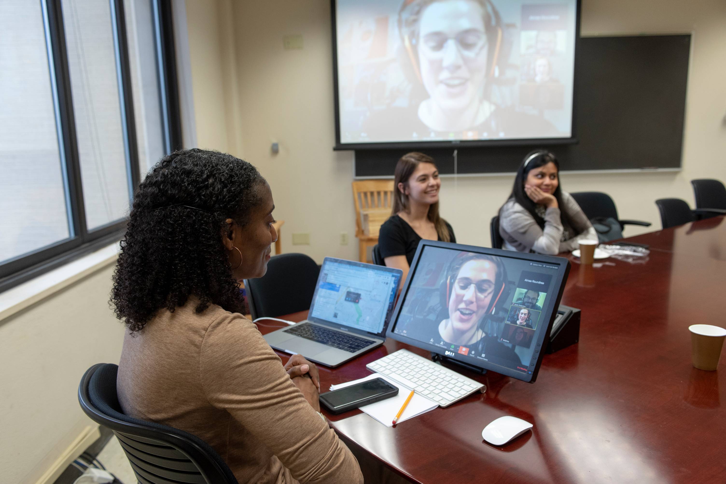 A professor leads a hybrid class of students in class and online.