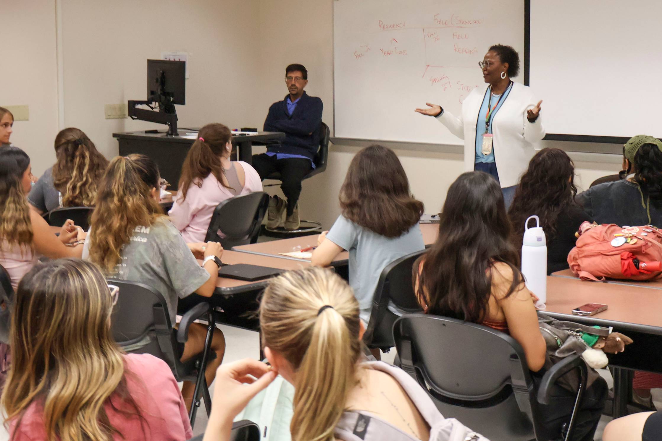 woman standing in front of classroom talking to students