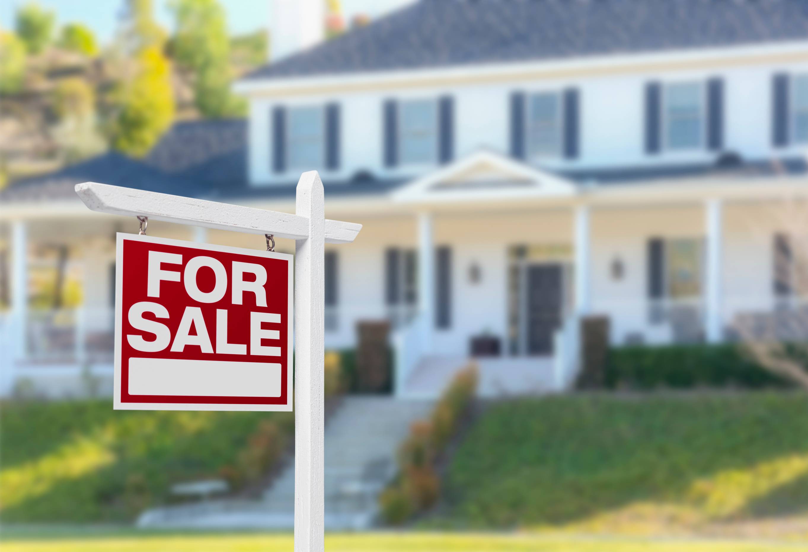 red white for sale sign with house blurred in background