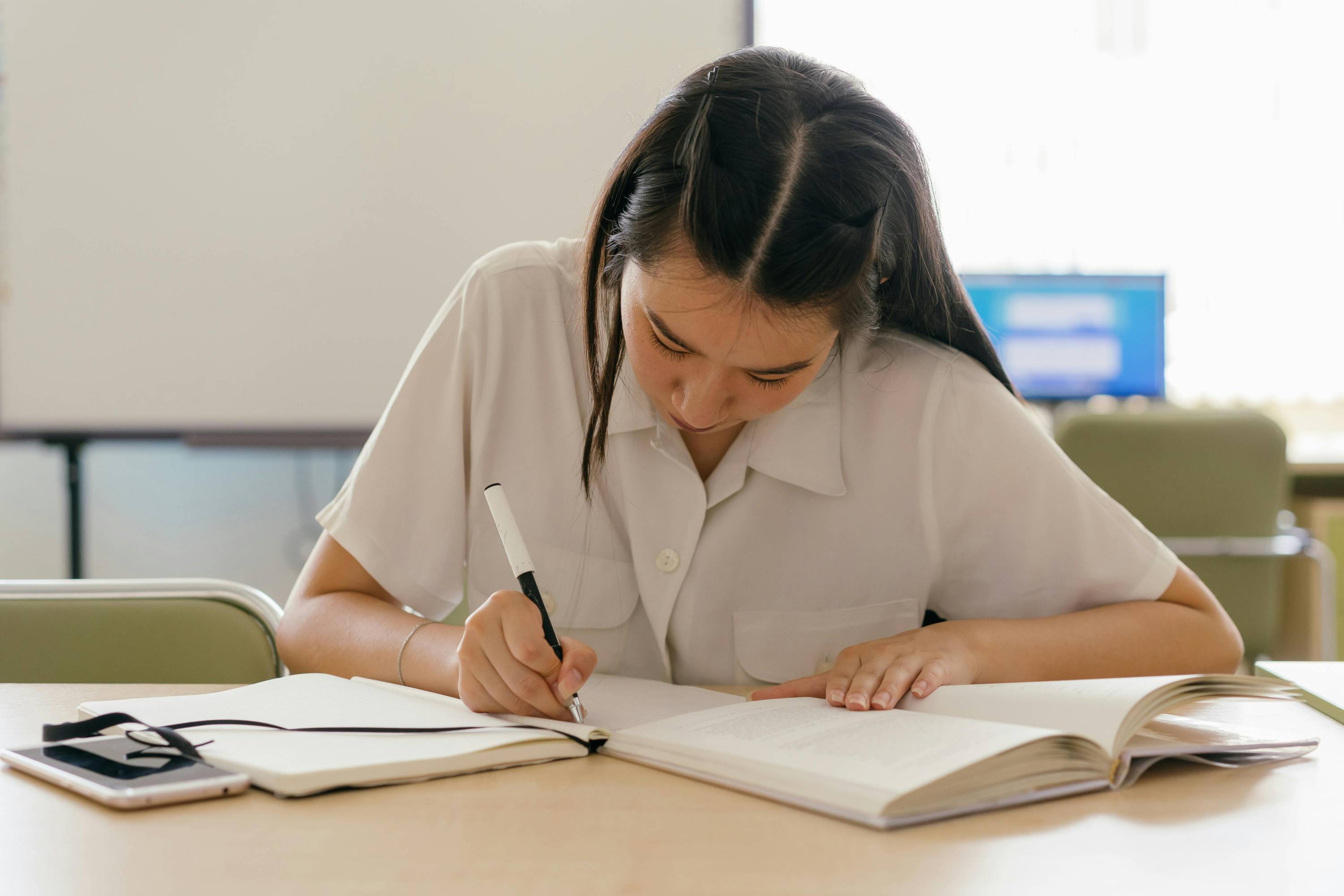 A student writing in a book at a desk