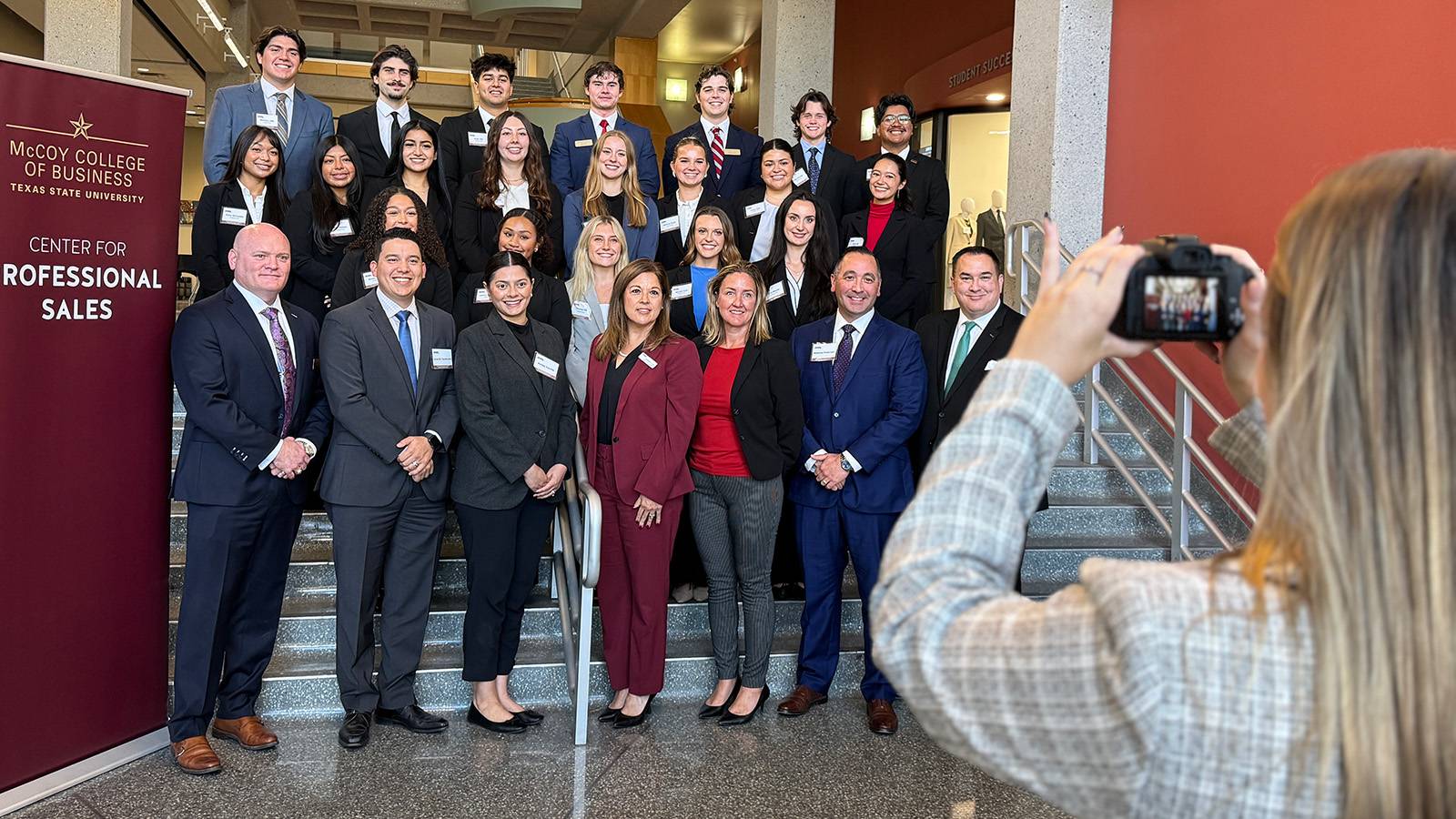 group of professionally dressed people pose for photo in McCoy Hall