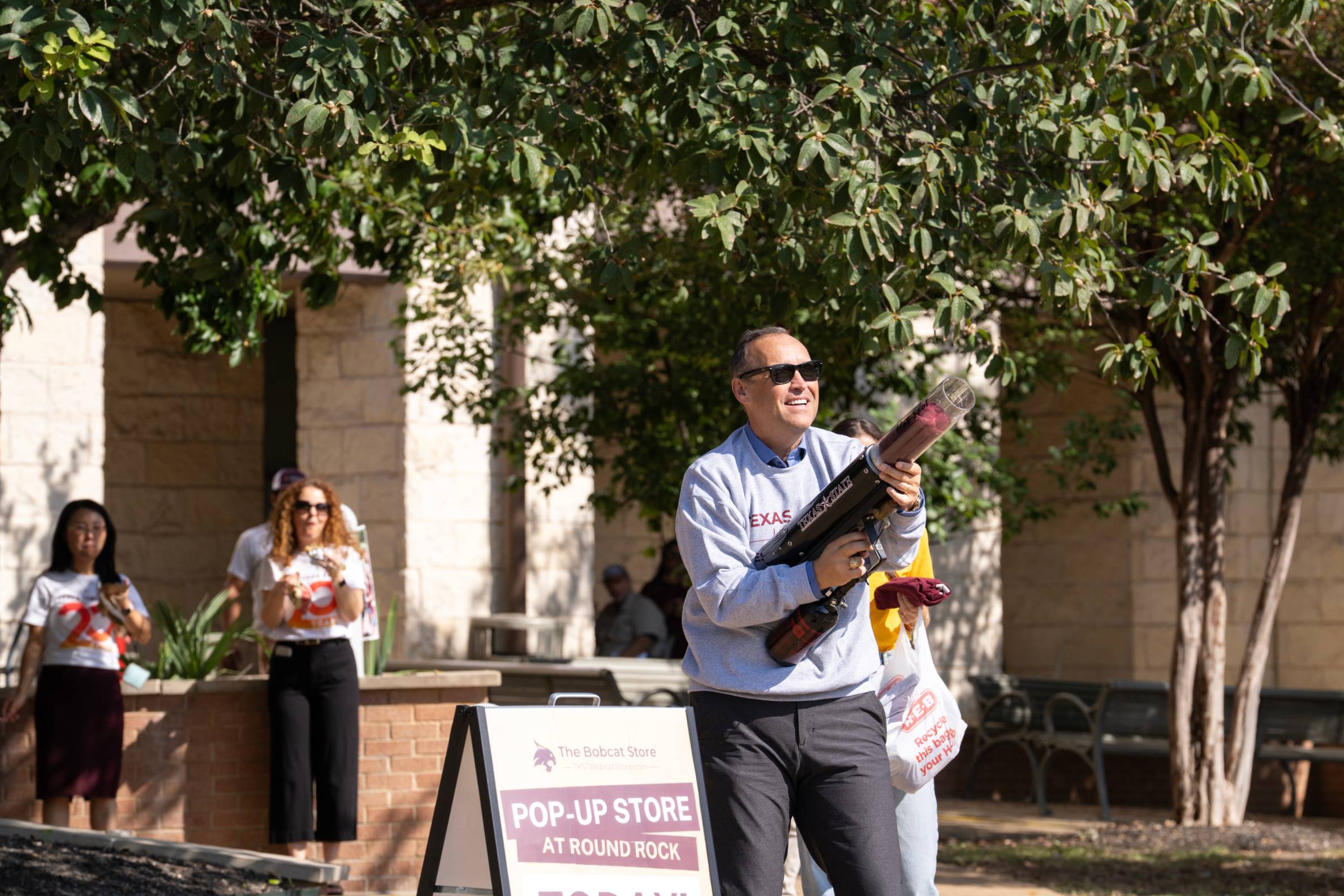president Kelly holding t-shirt cannon
