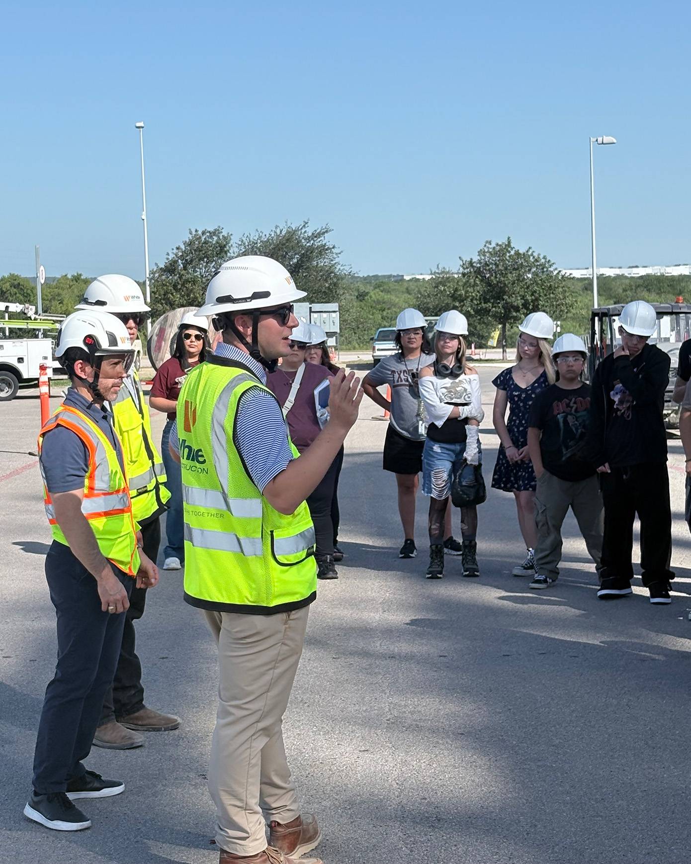 COTA leadership speaks to high school students while wearing hardhats.