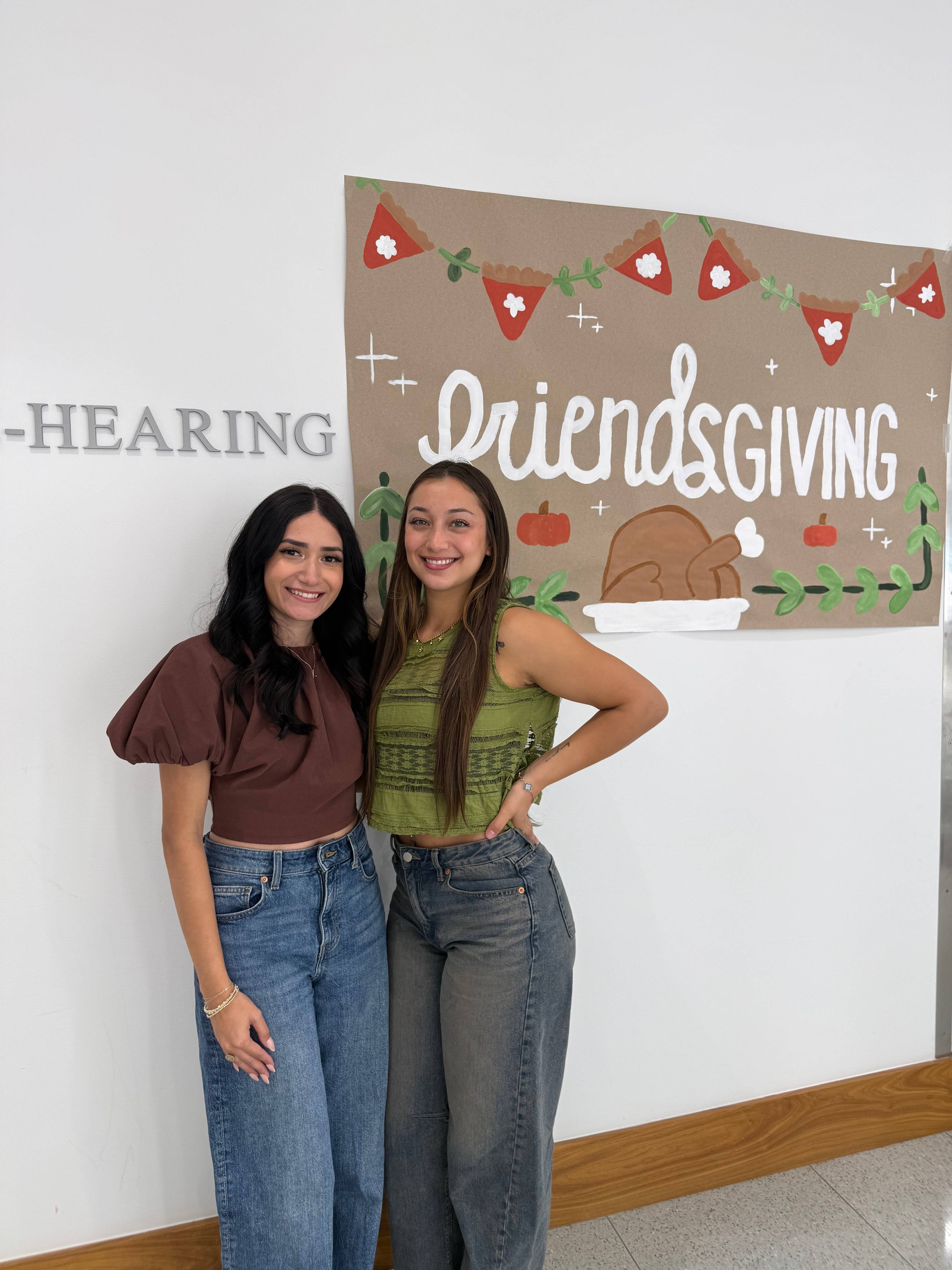 A couple of students posing next to a Friendsgiving poster.