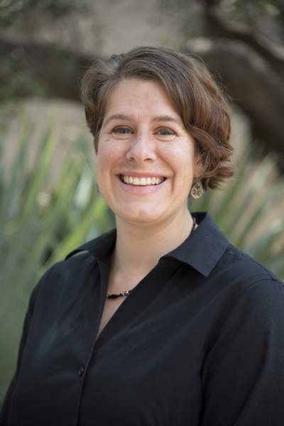 woman with short brown hair smiling at camera wearing a black button up shirt