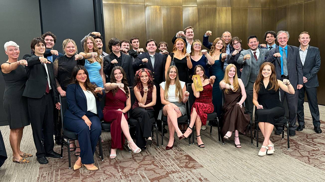 President Kelly Damphousse poses for a photo with the Advertising Team of students.