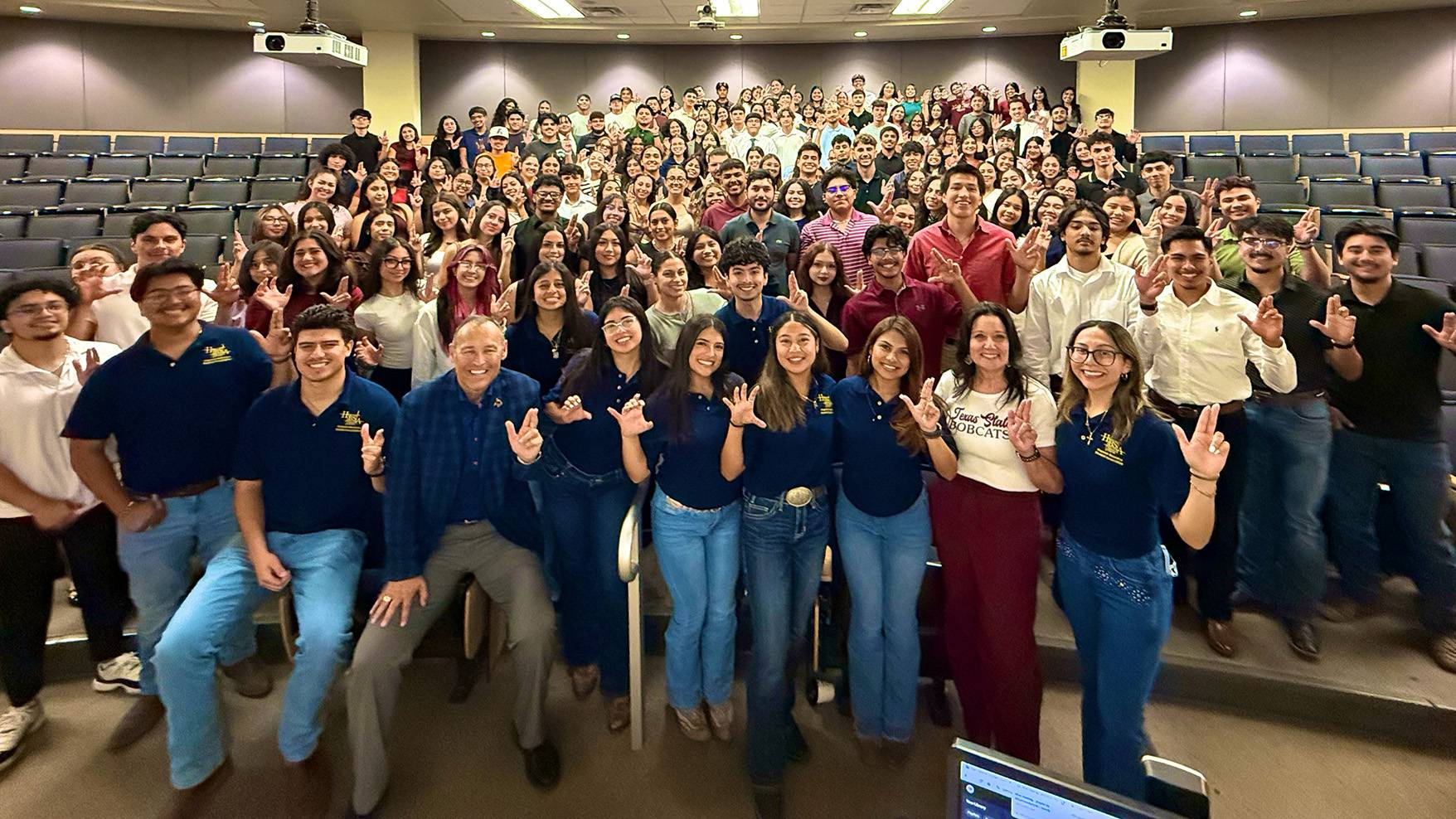 President Damphousse poses for a photo with a large group of students from the Hispanic Business Student Association.