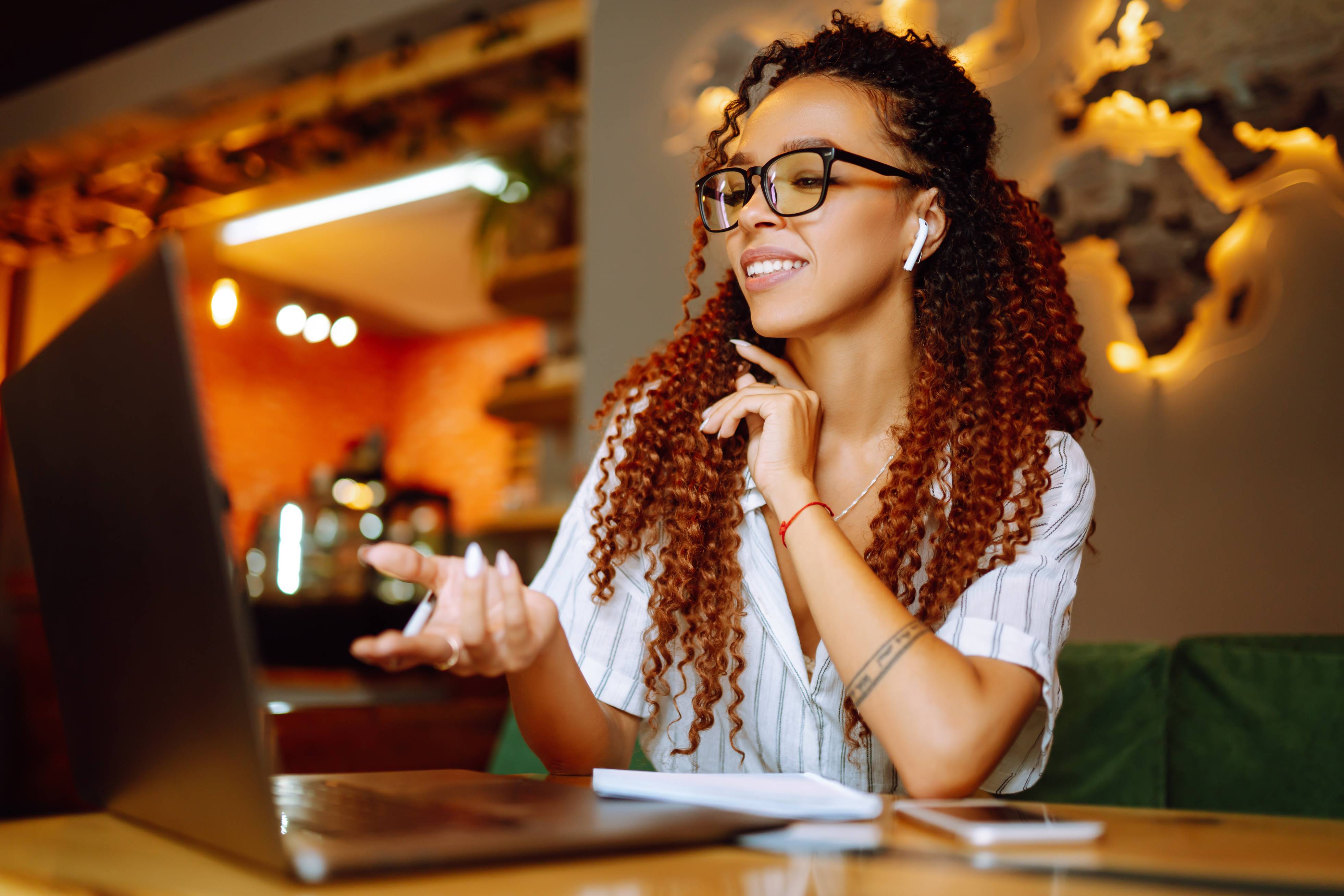 A woman sitting at a table talking in front of a laptop in a cafe
