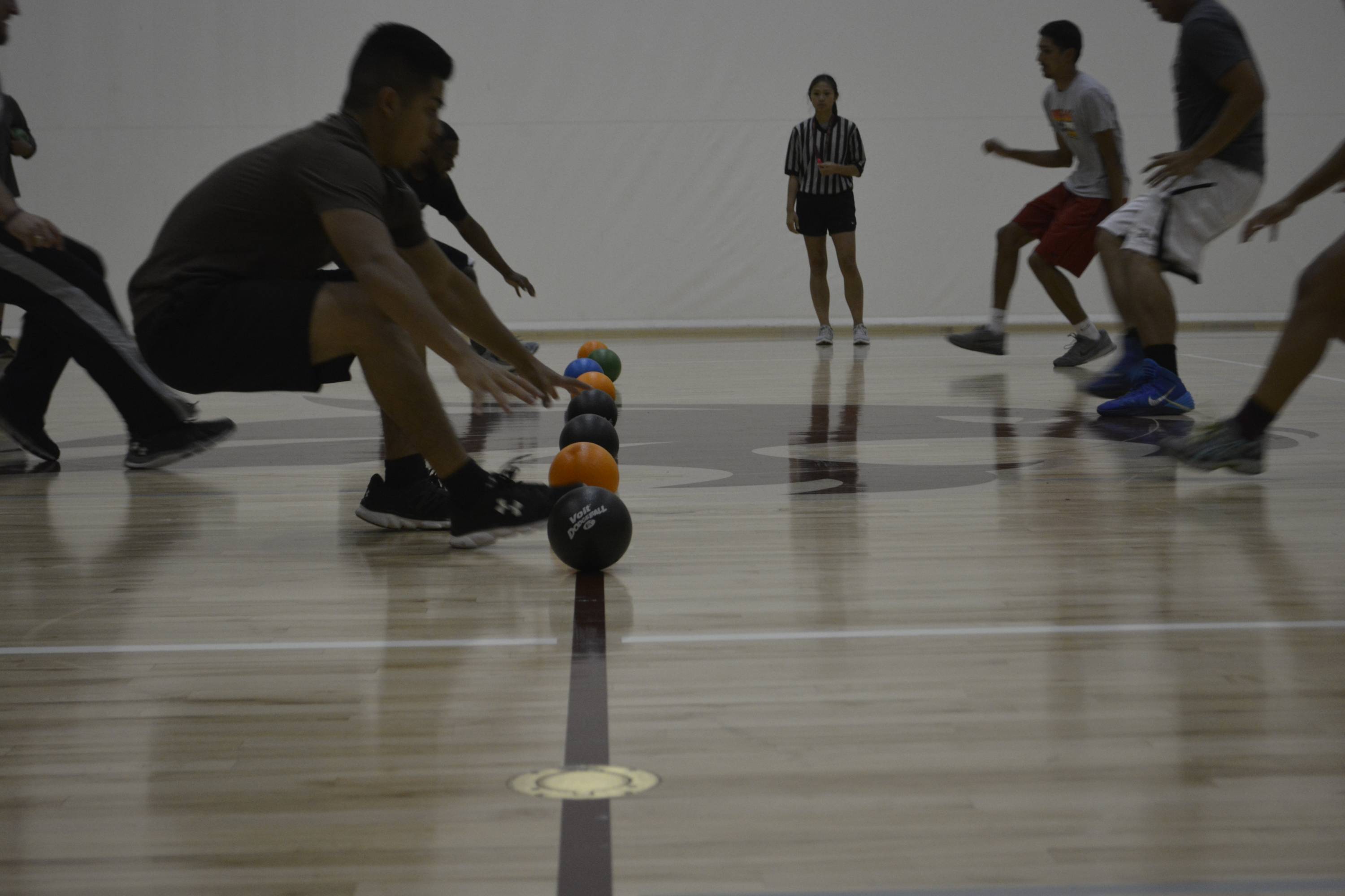 dodgeball participants race to grab dodgeballs at center court