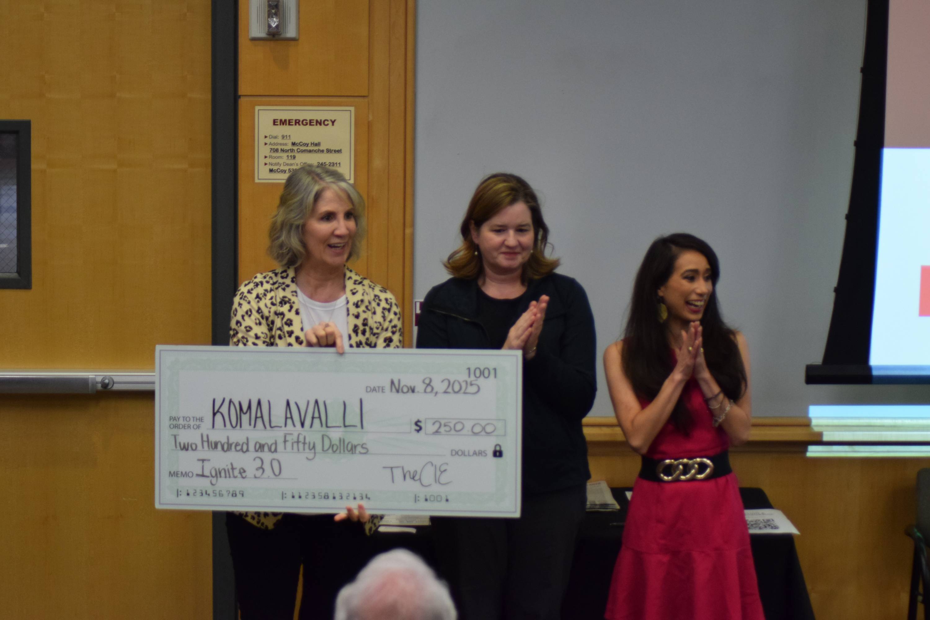 Judges holding a check for Komala Valli after she won third place at the Ignite 3.0 pitch competition.