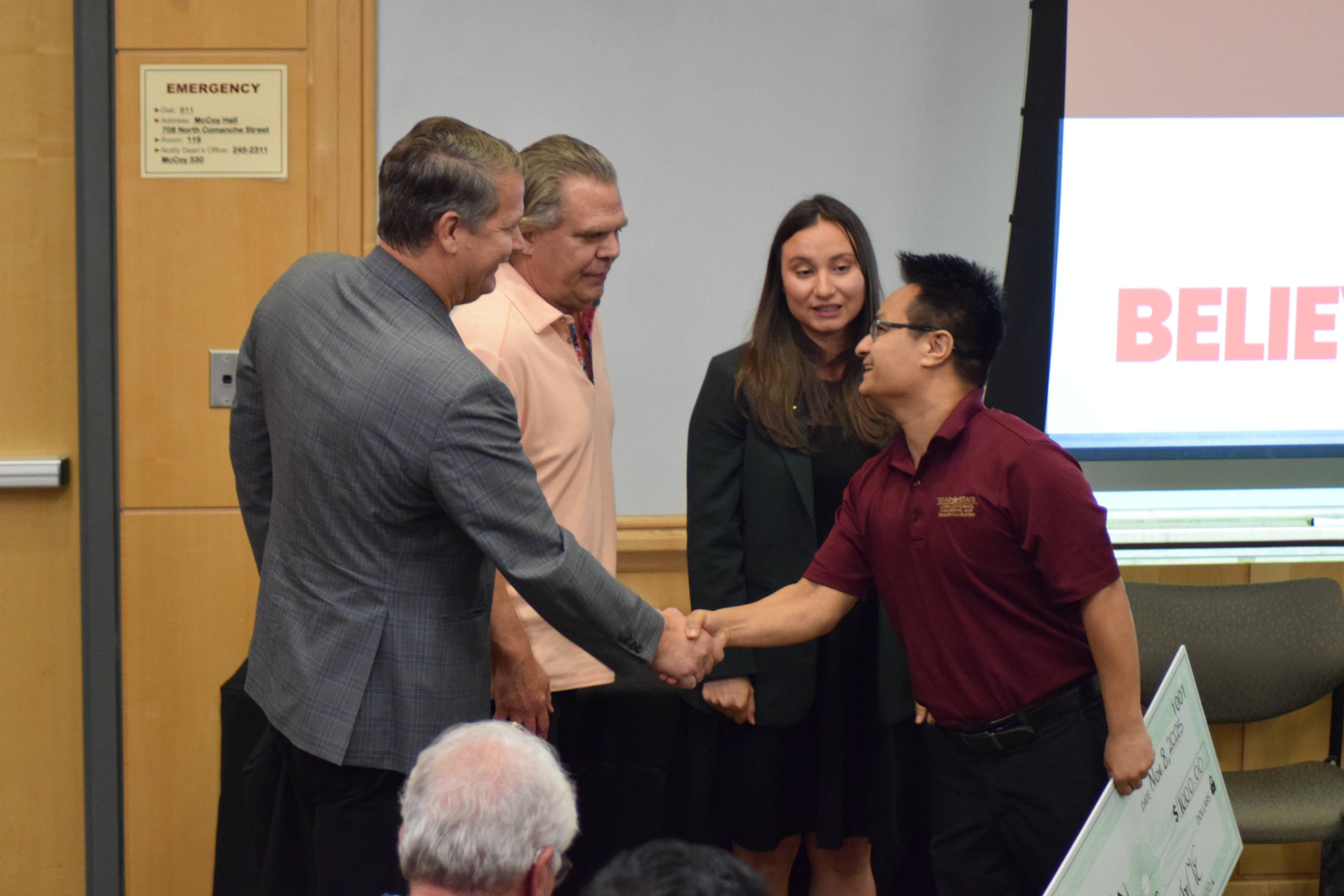 Rujan Kayastha shakes a judges hand after receiving a check for winning first place at the Ignite 3.0 pitch competition.