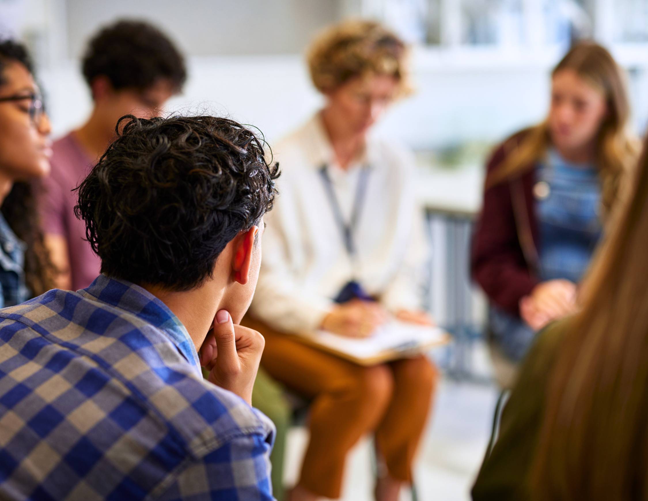 students in a white classroom listening to a teacher