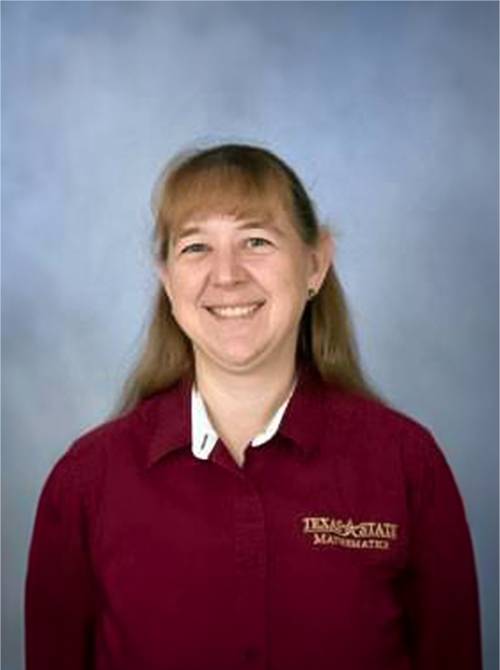 portrait of susan morey standing in front of a blue backdrop